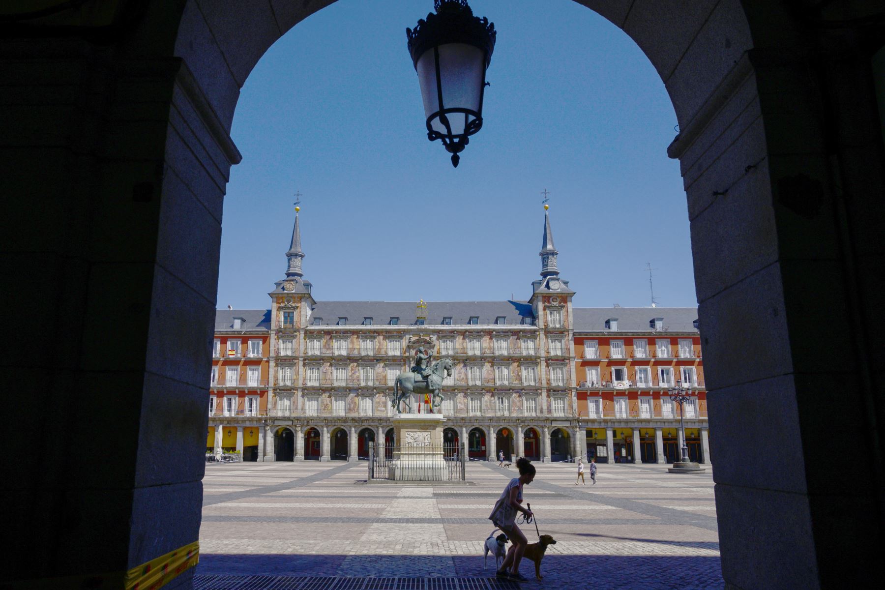 Una mujer pasea a sus perros en la Plaza Mayor de Madrid durante el cierre nacional para prevenir la propagación de la covid-19. Foto: AFP