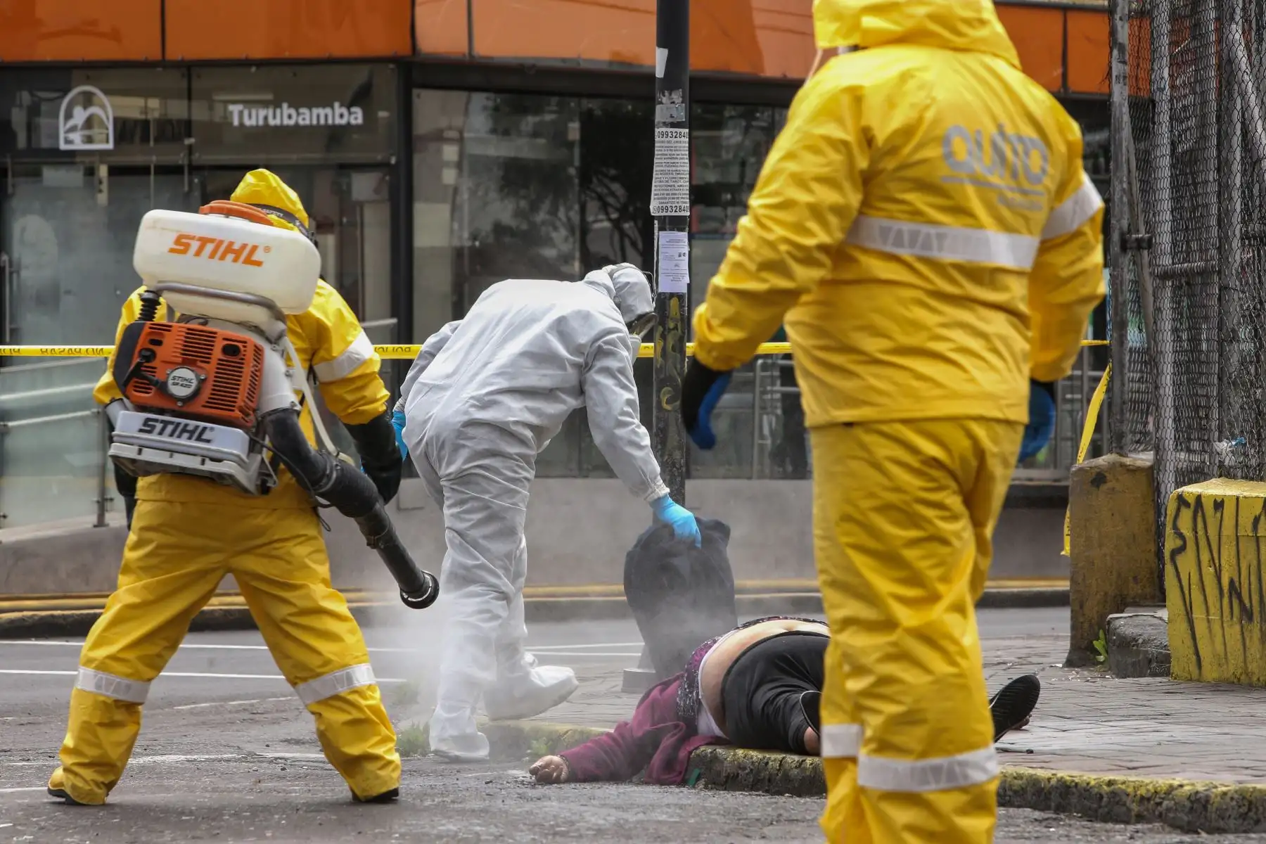 Un miembro de la policía de criminalística ecuatoriana desinfecta el cadáver de una mujer que murió por causas desconocidas en una calle de Quito. Foto: AFP