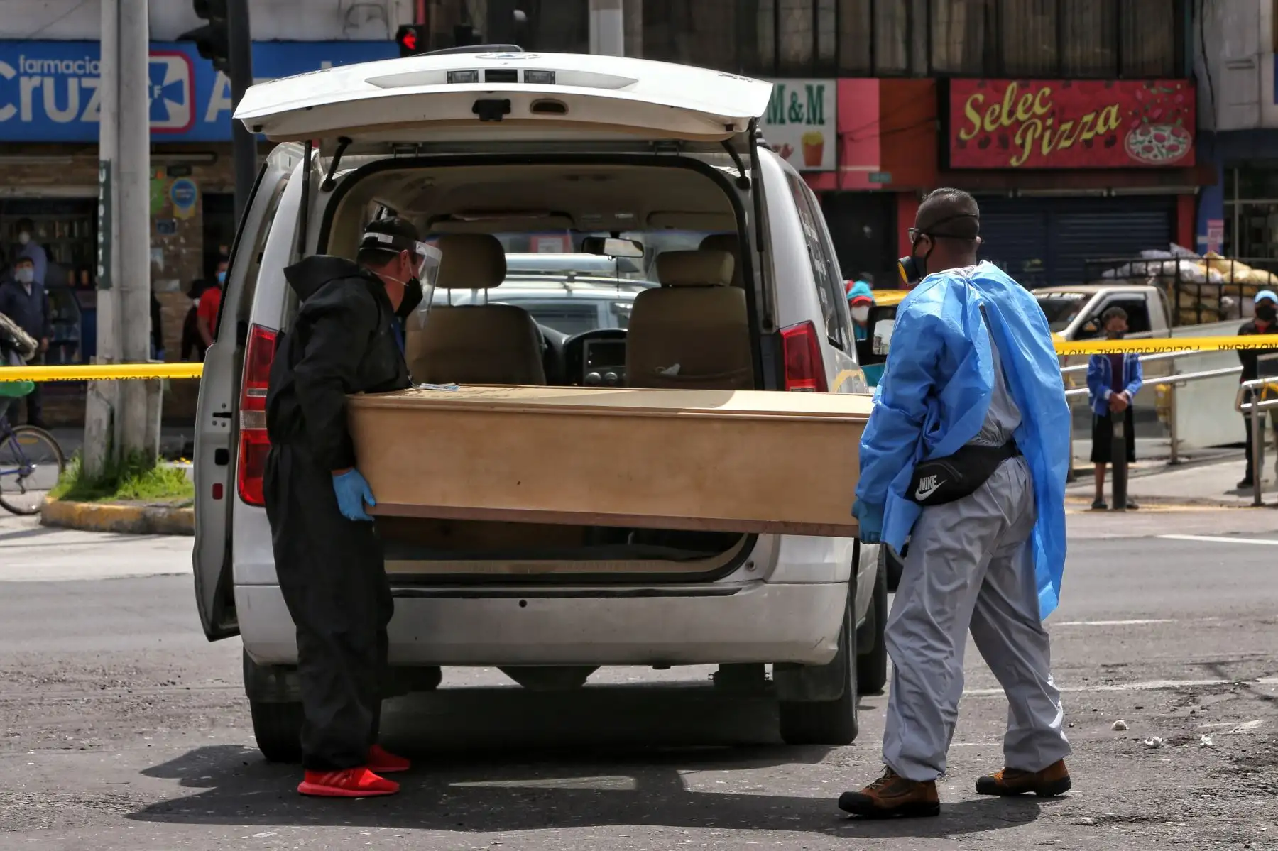 Miembros de una sala funeraria sacan el cuerpo de una mujer que murió por causas desconocidas en una calle de Quito. Foto: AFP