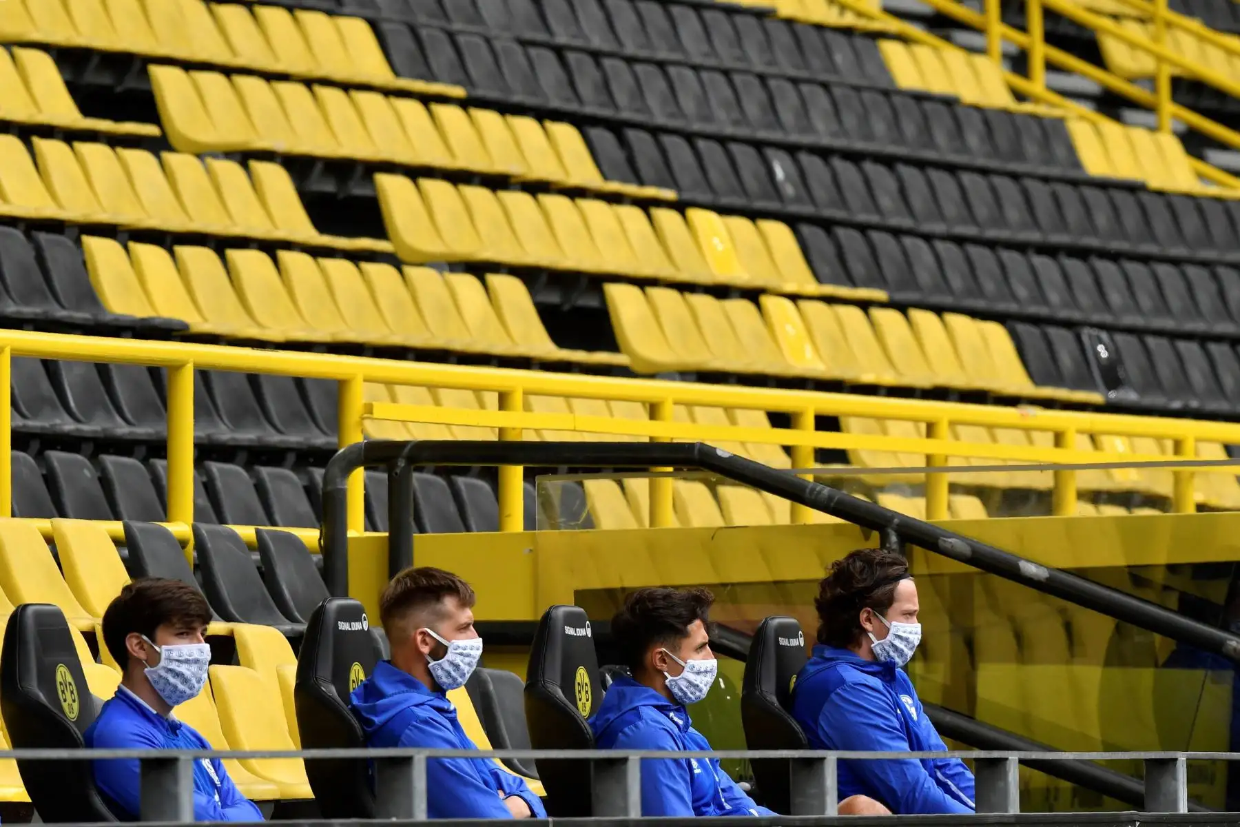 Los jugadores suplentes del Schalke 04 obsevan el partido desde el banquillo utilizando mascarillas. Foto: EFE