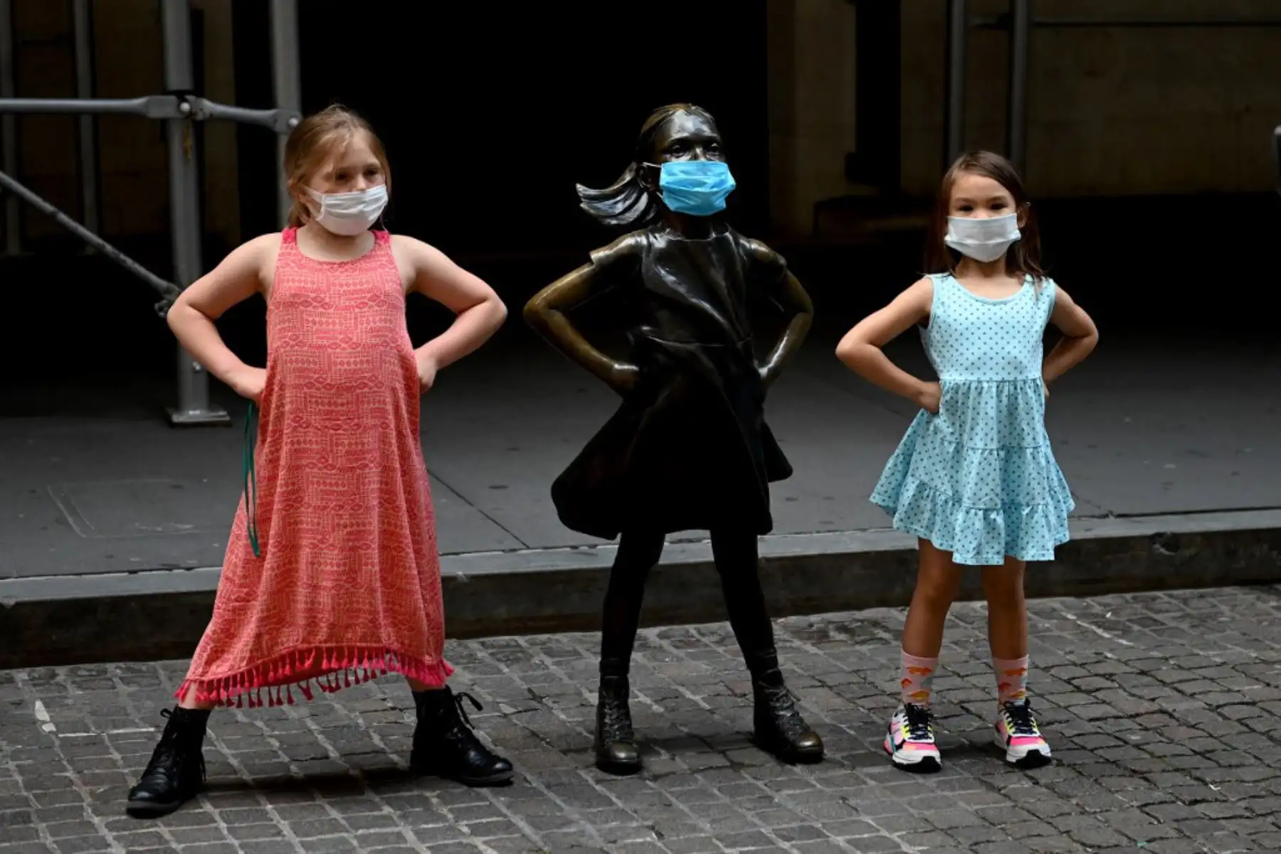 Dos jóvenes posan junto a la escultura de bronce enmascarada de la "Niña sin miedo" de Kristen Visbal, frente a la Bolsa de Nueva York. Foto: AFP