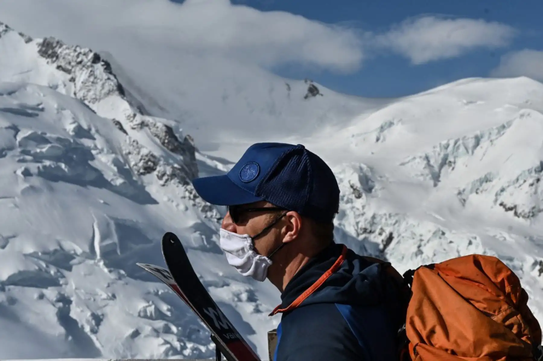 Un alpinista con una máscara facial llega a la cima de 