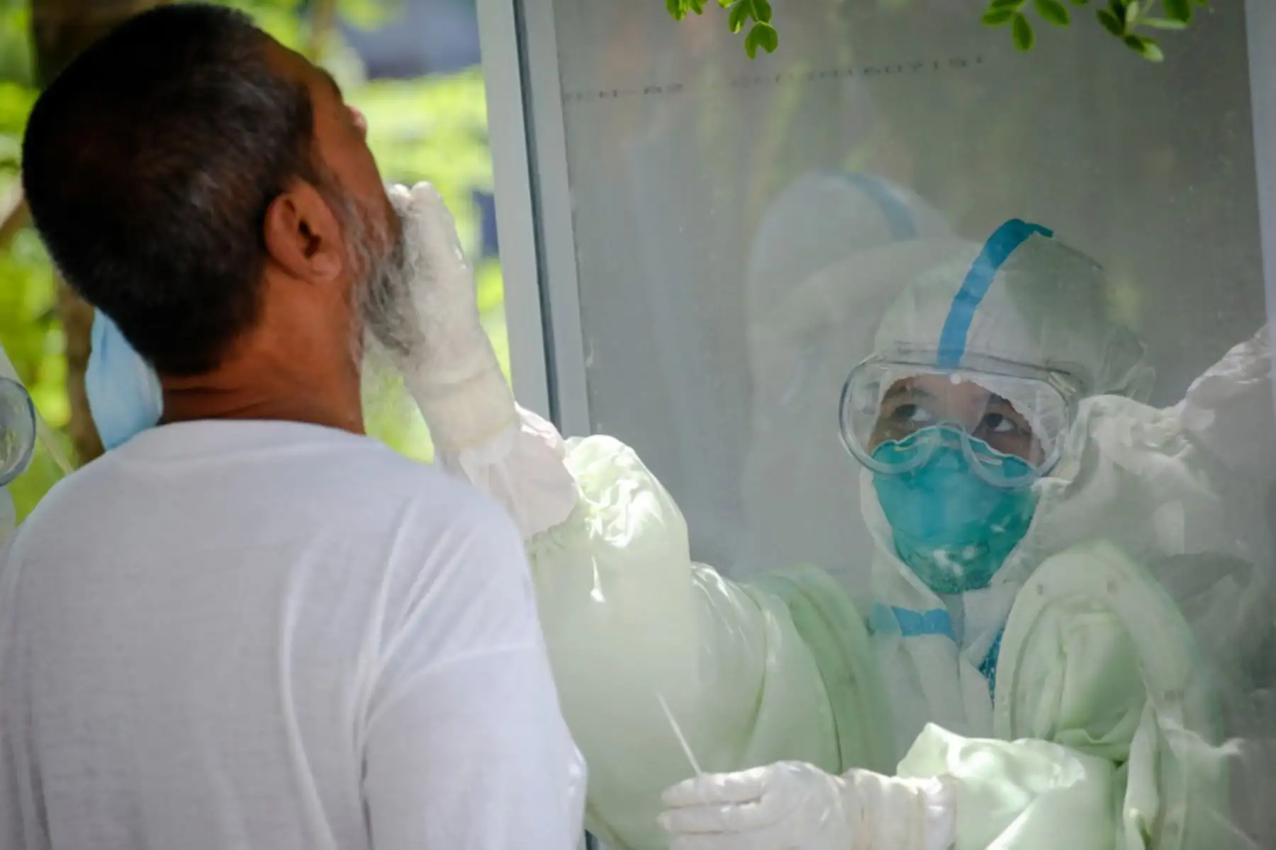 Un médico que usa equipo de protección toma una muestra de hisopo de un monje para analizar el coronavirus COVID-19 en un centro de cuarentena en Yangon. Foto: AFP