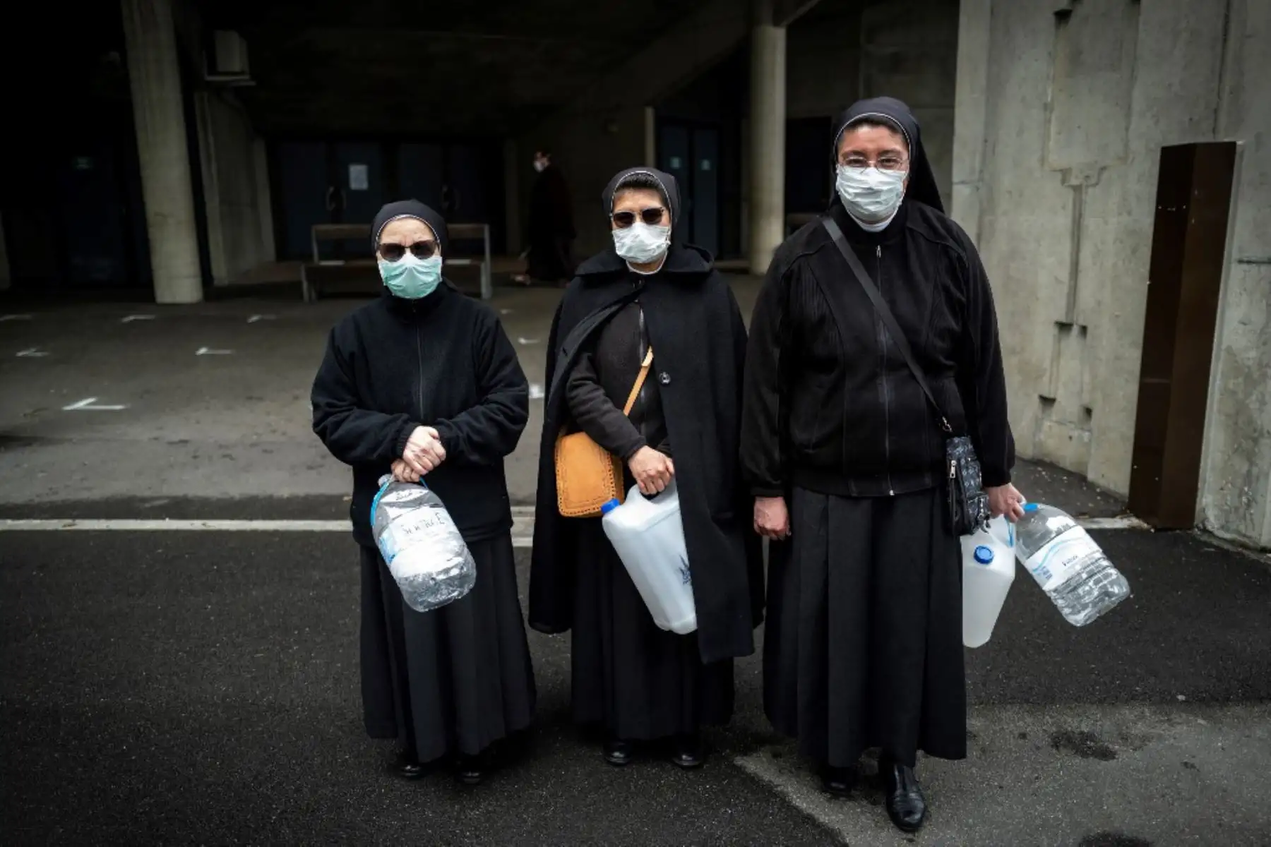 Peregrinos con máscaras faciales esperan para recoger agua en el Santuario de Nuestra Señora de Lourdes en Francia. Foto: AFP