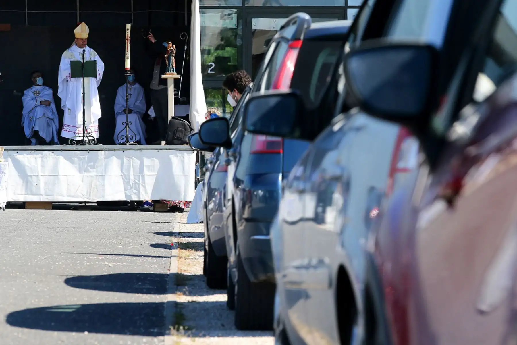 El obispo de Chalon, Francois Touve, dirige la misa dominical mientras unos 500 feligreses se sientan en sus vehículos mientras asisten a la misa al aire libre celebrada en un estacionamiento en Francia. Foto: AFP