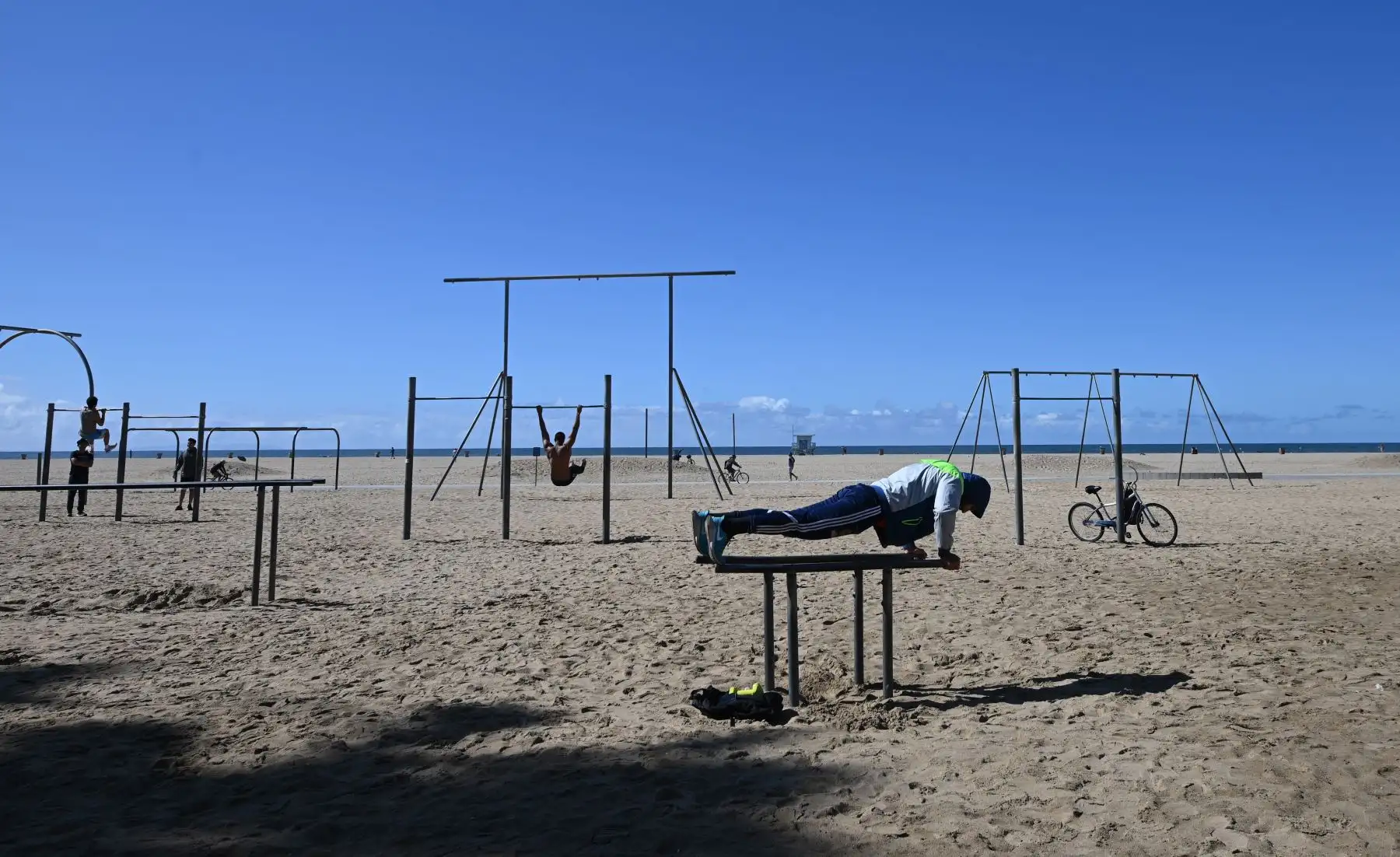 Los hombres hacen ejercicio a una distancia segura el uno del otro en Muscle Beach en Santa Mónica, California. Foto: AFP