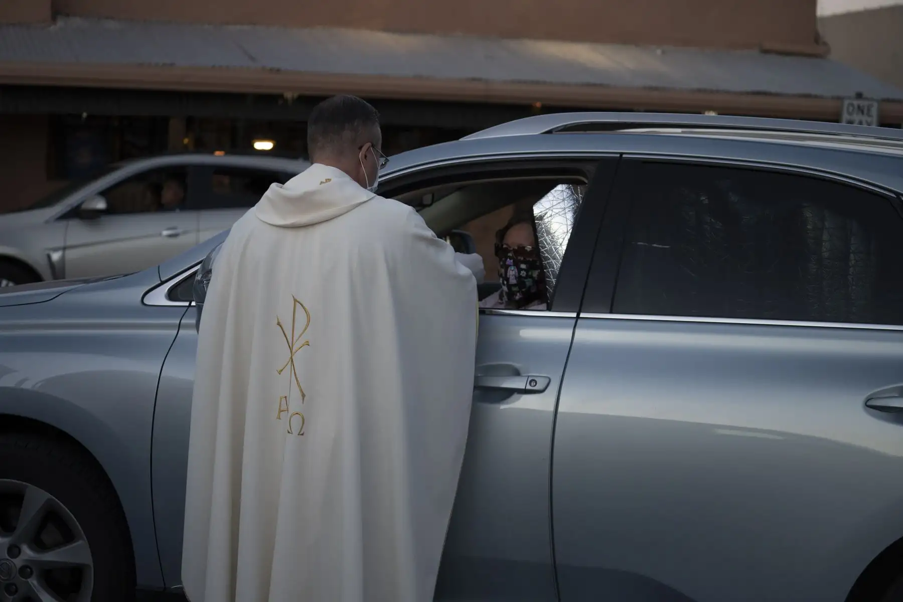 El padre Christoper Williams da la comunión a los feligreses en sus automóviles fuera de la Basílica de San Albino. Foto: AFP