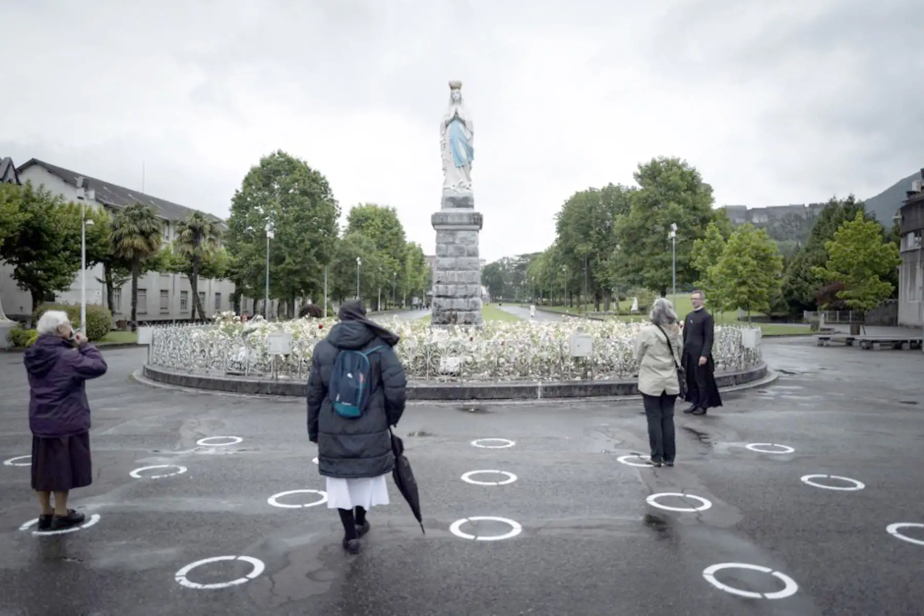 Peregrinos se paran en carteles de distanciamiento social frente a la estatua de La Virgen coronada en el Santuario de Nuestra Señora de Lourdes en Francia. Foto: AFP