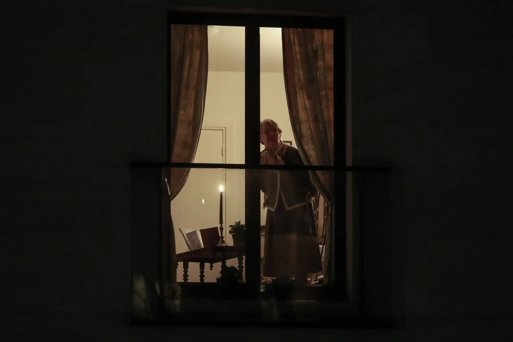 Una mujer se encuentra cerca de una vela encendida cerca de su ventana durante un aplauso diario a las 8 en punto en apoyo de los trabajadores médicos en París. Foto: AFP