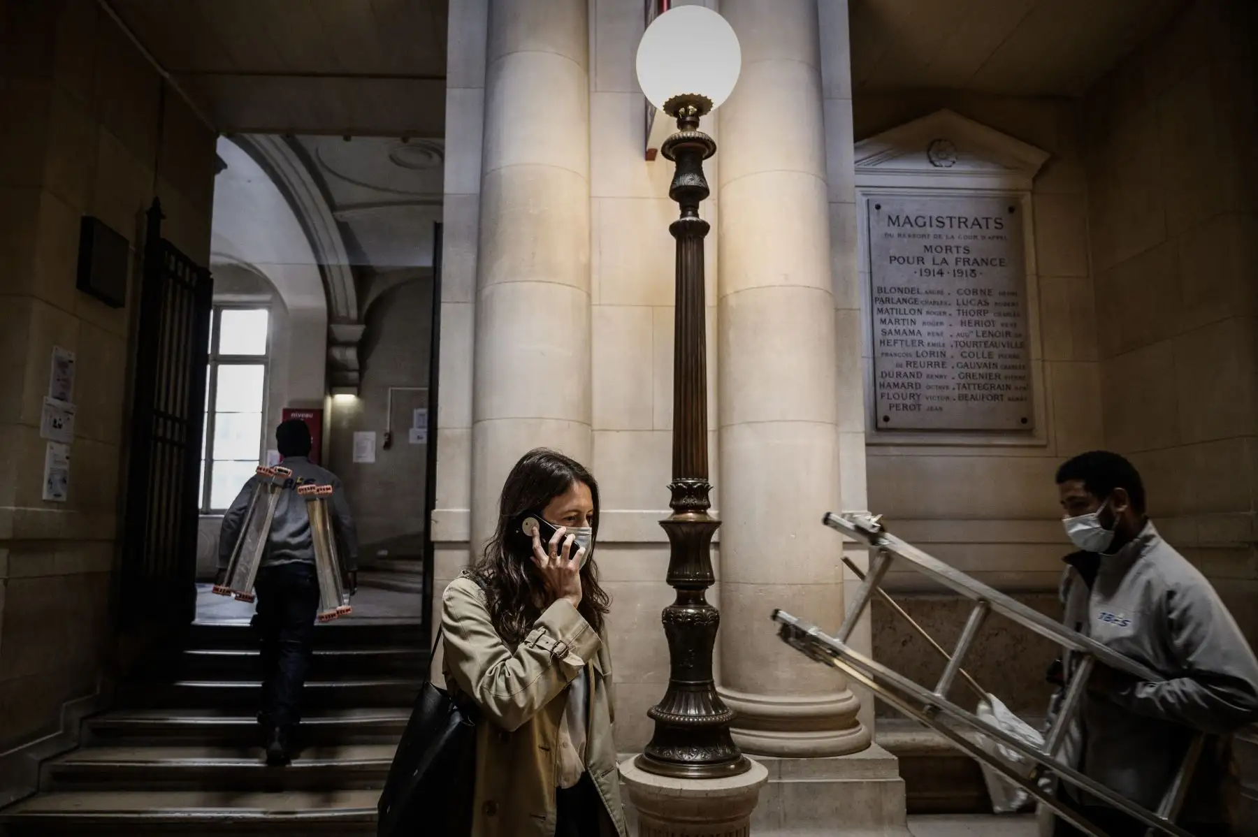 La abogada francesa Noemie Saïdi Cottier habla por teléfono mientras los trabajadores pasan por un pasillo del Palacio de Justicia. Foto: AFP