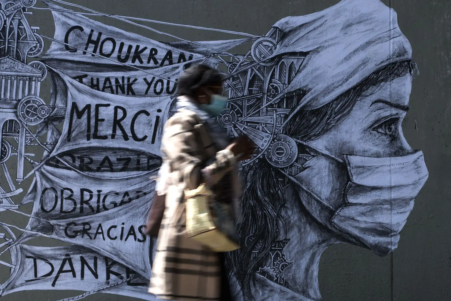 Una mujer que lleva una máscara protectora pasa junto a un disfraz del artista callejero francés Ardif, en París. Foto: AFP
