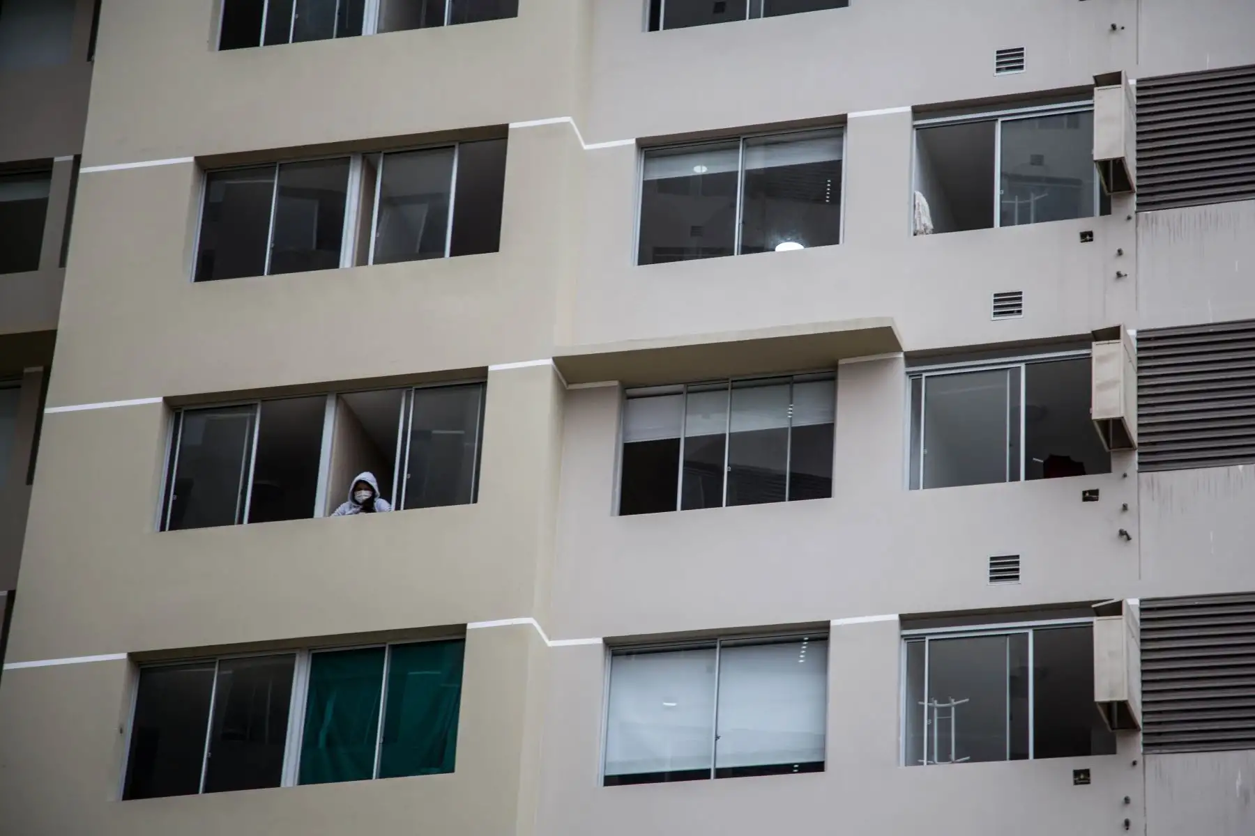 La fotografía muestra a una paciente internada mientras se asoma por la ventana de una habitación, en la Villa Panamericana, habilitada para alojar a casos positivos de coronavirus, en Lima (Perú). Foto: EFE