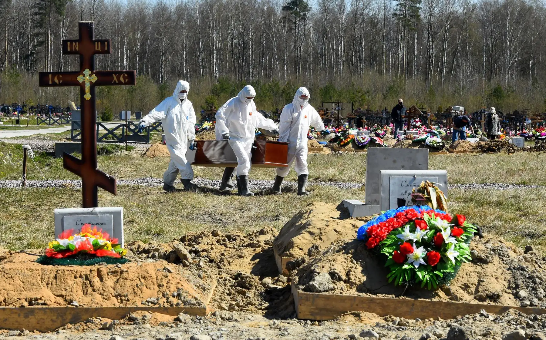 Los trabajadores del cementerio que usan equipo de protección entierran a una víctima de coronavirus en un cementerio en las afueras de San Petersburgo. Foto: AFP