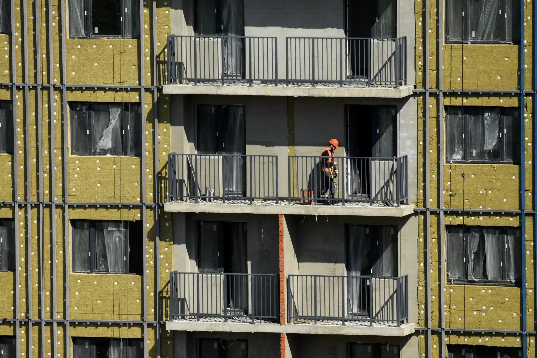 Un trabajador camina por el balcón de un edificio residencial en construcción en Moscú. Foto: AFP