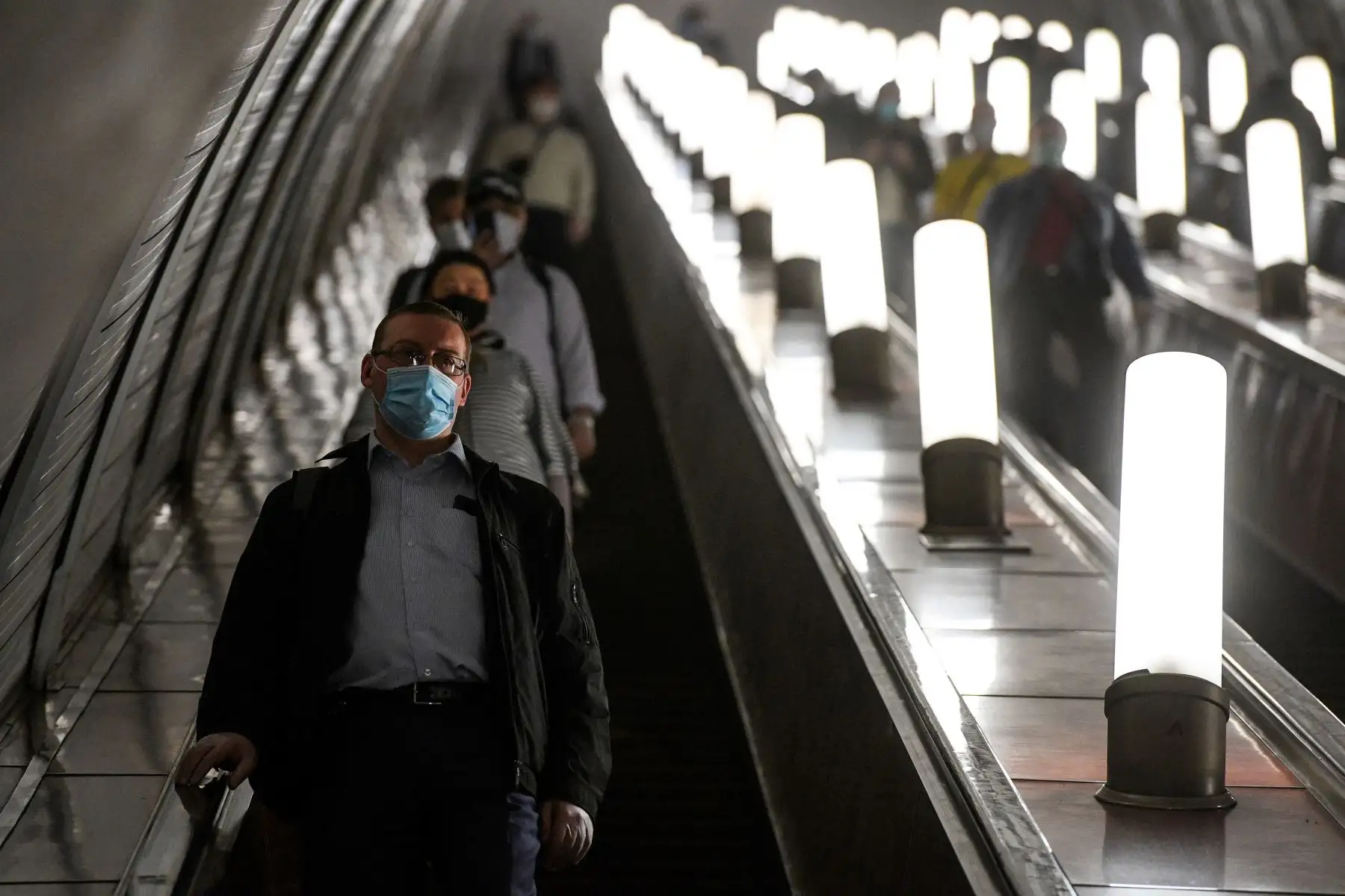 Las personas que usan máscaras faciales suben por una escalera mecánica en la estación de metro Savyolovskaya el primer día de uso obligatorio de máscaras y guantes en el transporte público de Moscú. Foto: AFP