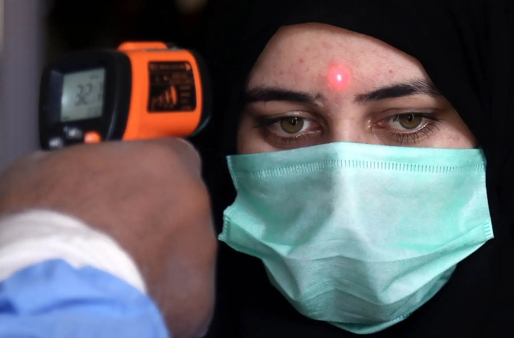 Un trabajador de una estación de tren mide la temperatura de una pasajera en Karachi, Pakistán. Foto: EFE