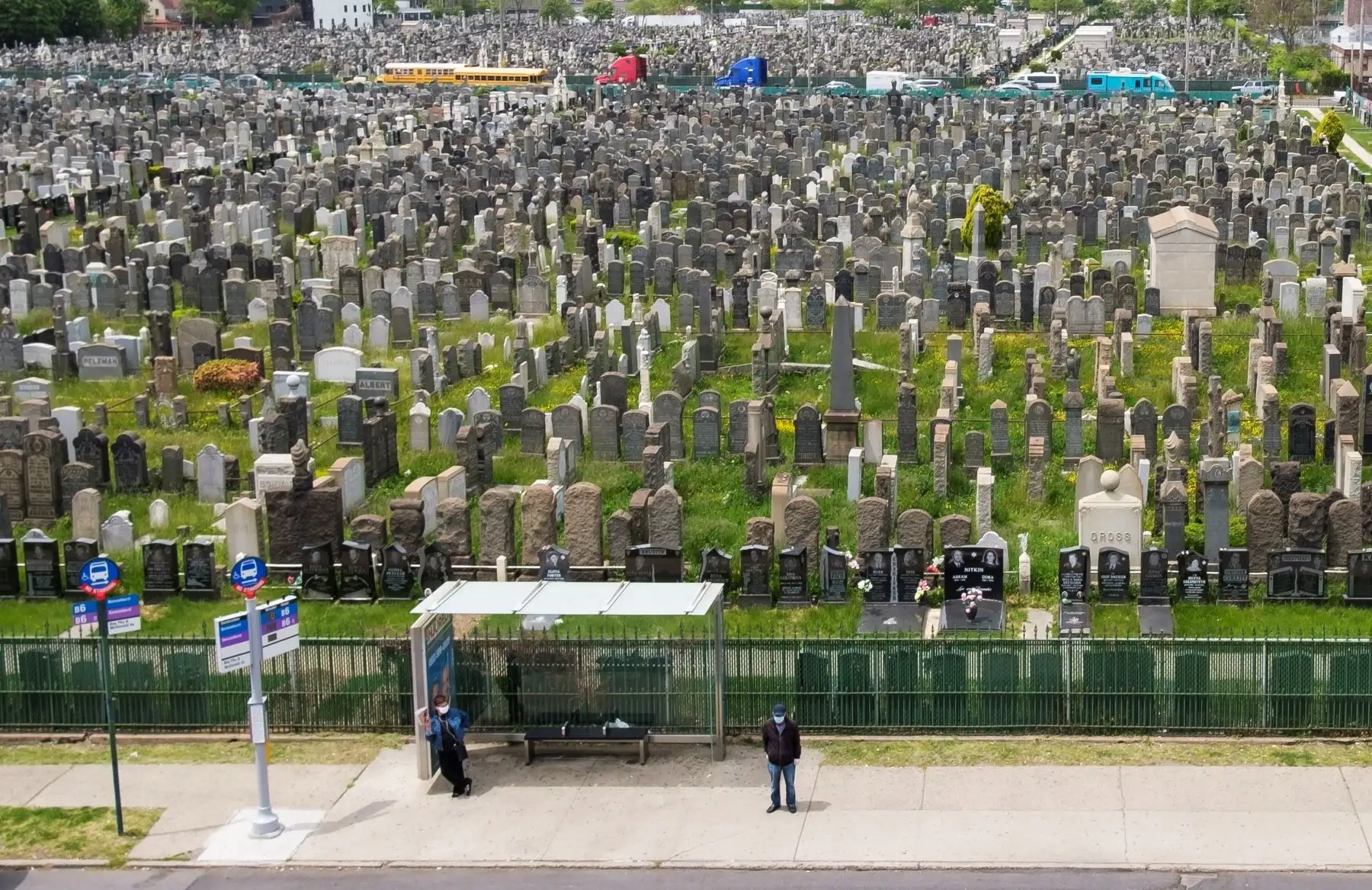 Dos personas esperan en bus en un paradero ubicado al lado del cementerio, en Brooklyn. Foto: EFE