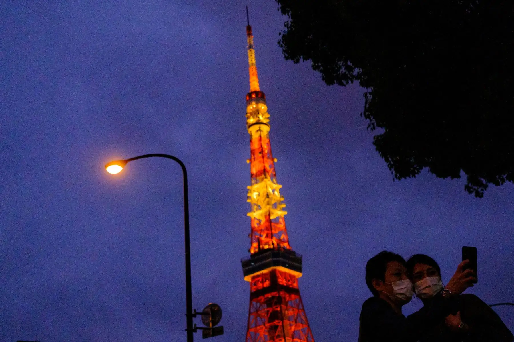 Las personas que usan máscaras faciales en medio de preocupaciones por el coronavirus covid-19 toman selfies ante la Torre de Tokio en Tokio

Foto: AFP