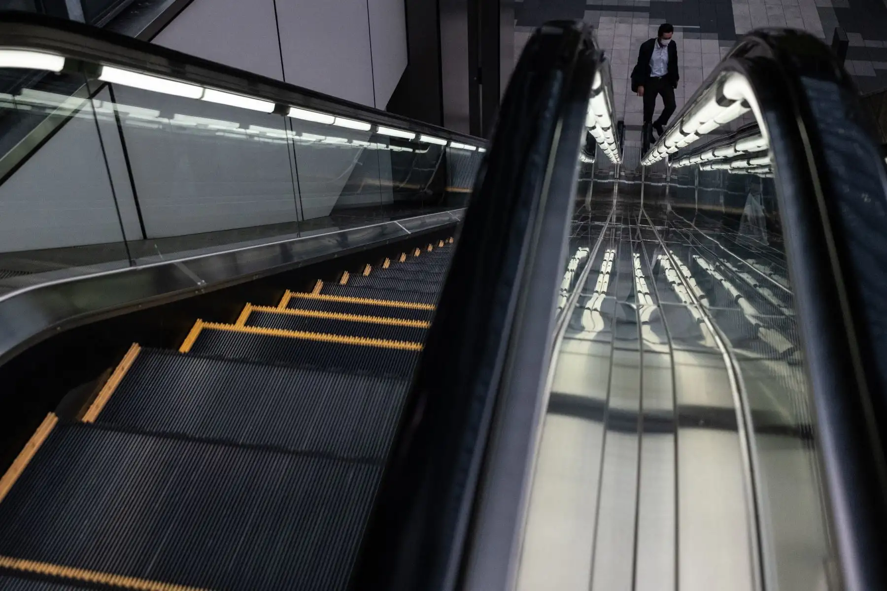 Un hombre con una máscara facial en medio de preocupaciones por el coronavirus covid-19 camina junto a una escalera mecánica en el área de Akihabara en Tokio 

Foto: AFP