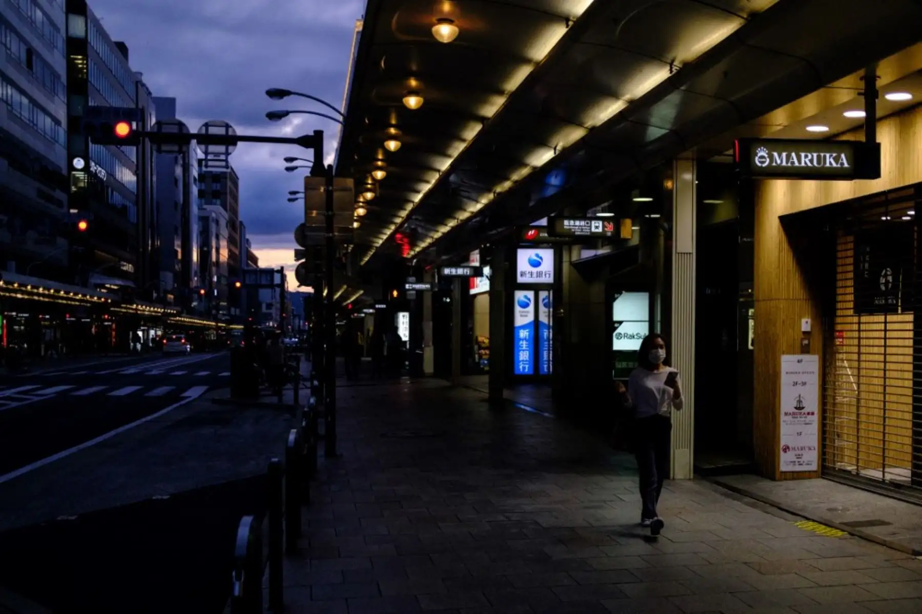 Una mujer con una máscara facial en medio de preocupaciones por el coronavirus covid-19 camina en una calle con tiendas cerradas en Kioto Foto: AFP
