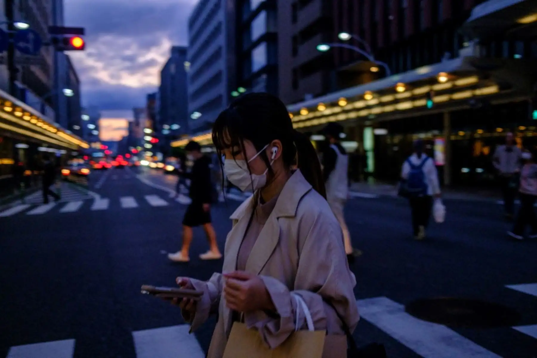 Una mujer con una máscara facial en medio de preocupaciones por el coronavirus covid-19 camina en una calle de Kioto 

Foto: AFP