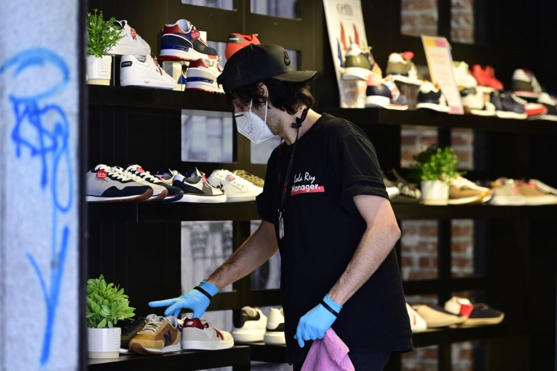 Un empleado que usa una máscara y guantes ajusta la exhibición de zapatos en una tienda en Madrid , ya que el uso de máscaras se hizo obligatorio en público donde no es posible el distanciamiento social. 
Foto: AFP