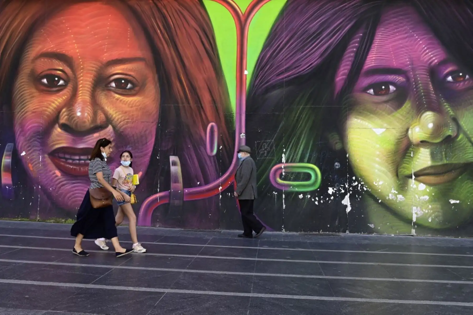 Las personas que usan máscaras pasan junto a un mural en Madrid, ya que el uso de máscaras se hizo obligatorio en público donde no es posible el distanciamiento social. 
Foto: AFP