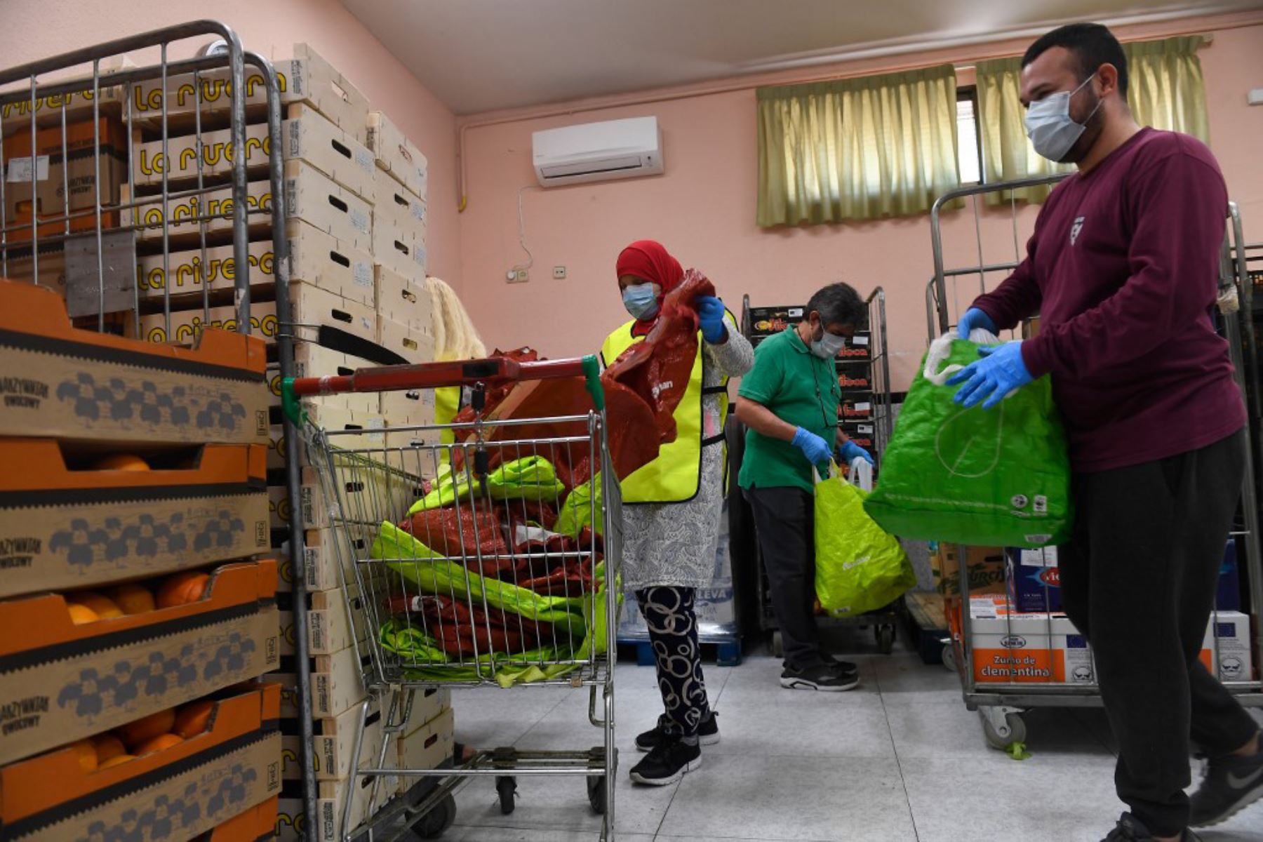 Los voluntarios preparan raciones de alimentos para distribuir a las personas necesitadas en el banco de alimentos de la Asociación Nazaret en Madrid.
Foto: AFP