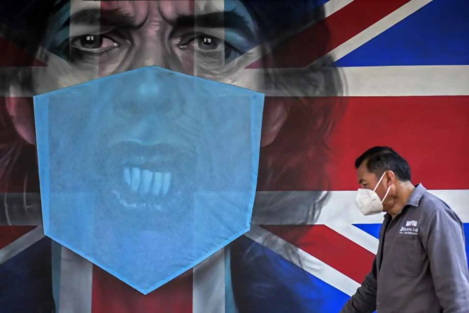 Un hombre camina junto a un mural que representa al cantante inglés Mick Jagger con una máscara protectora en la Ciudad de México, en medio de la nueva pandemia de coronavirus. 
Foto: AFP