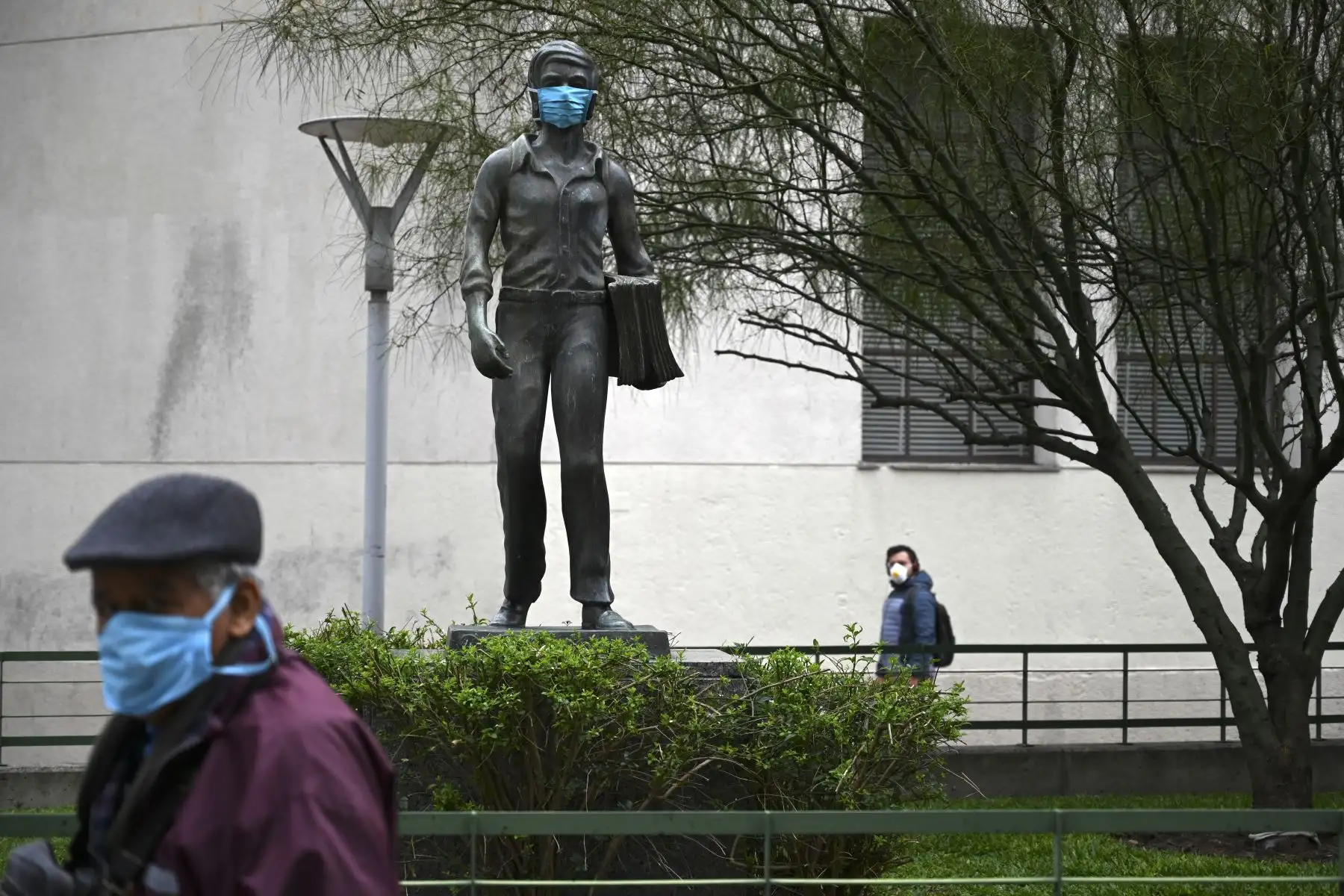 Una escultura que representa a un repartidor de periódicos usa una máscara facial en Montevideo. Foto: AFP