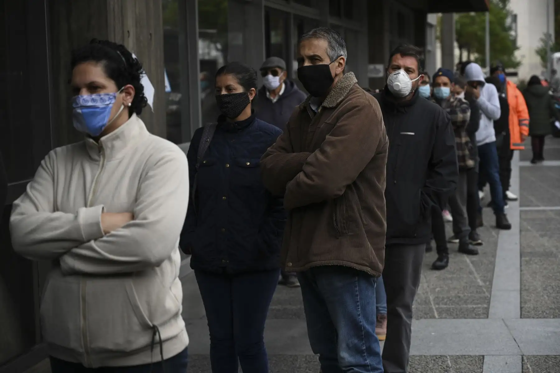 Personas con máscaras faciales se alinean frente al edificio de seguridad social de propiedad estatal uruguaya en Montevideo. Foto: AFP