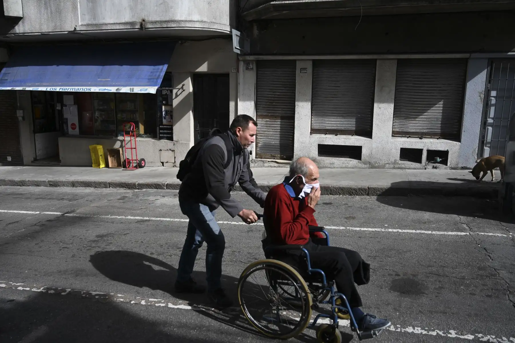 Un anciano con una máscara facial es empujado en su silla de ruedas en Montevideo. Foto: AFP