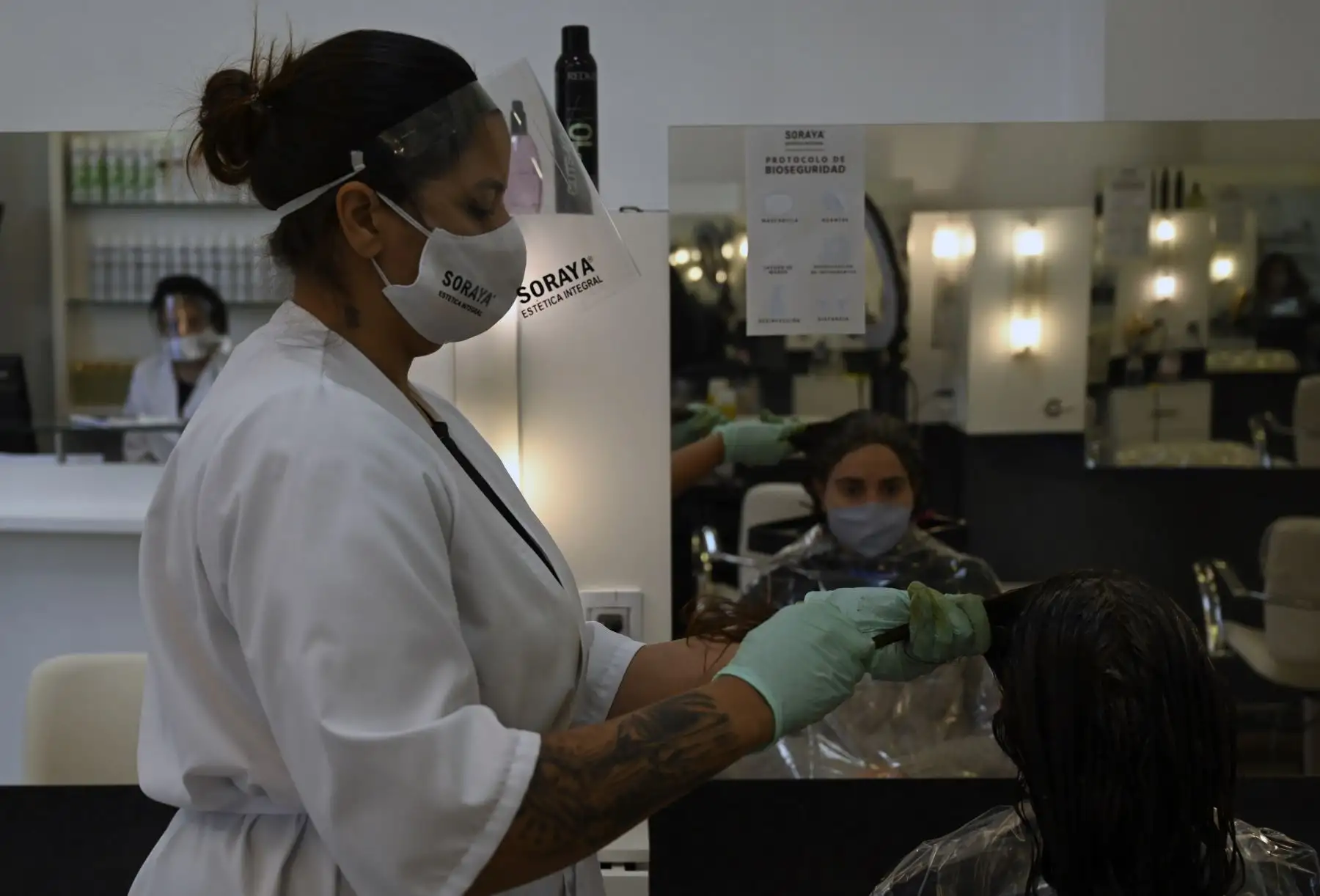 Un empleado usa un protector facial en un salón de peluquería en Montevideo. Foto: AFP