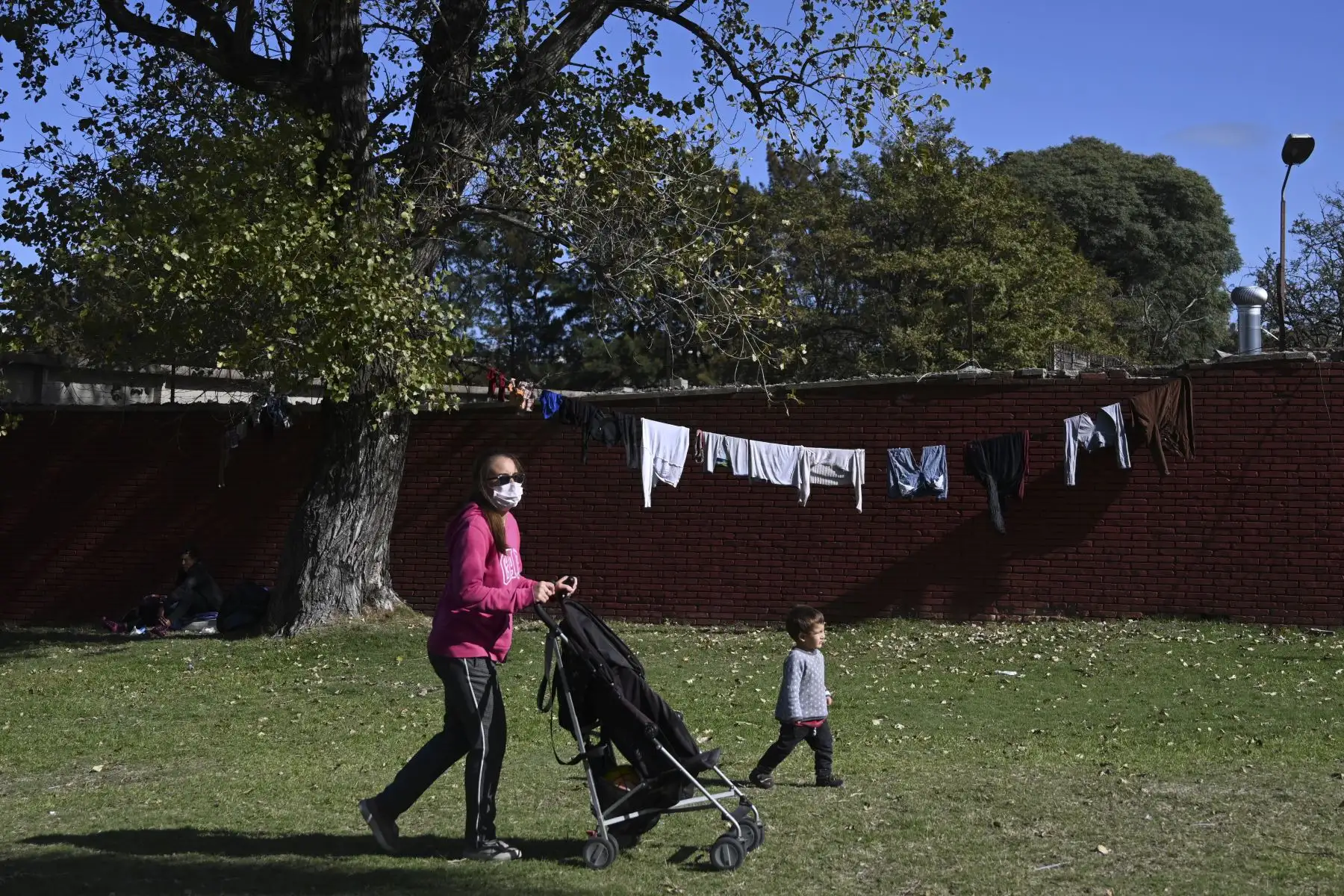 Una mujer usa una máscara facial mientras camina con su hijo en un parque en Montevideo. Foto: AFP