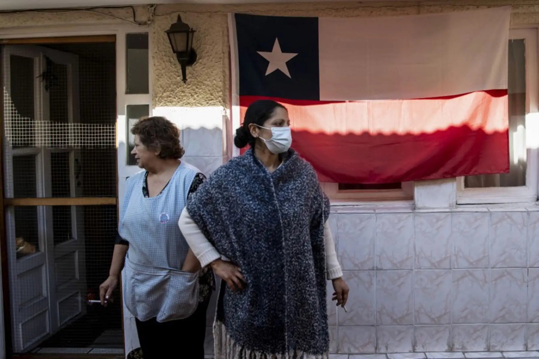 Una familia espera recibir una canasta de alimentos entregado por trabajadores municipales, en Chile. Foto: AFP
