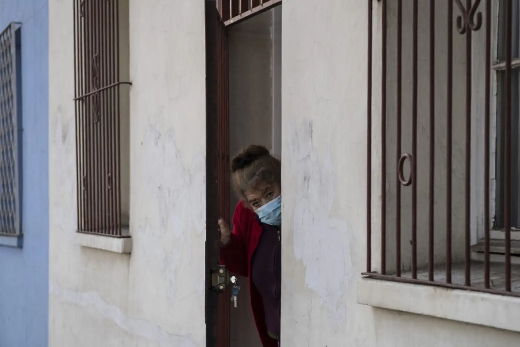 Una mujer con una máscara facial observa la entrega de cajas con alimentos por parte de trabajadores municipales a familias económicamente afectadas, en Chile. Foto: AFP