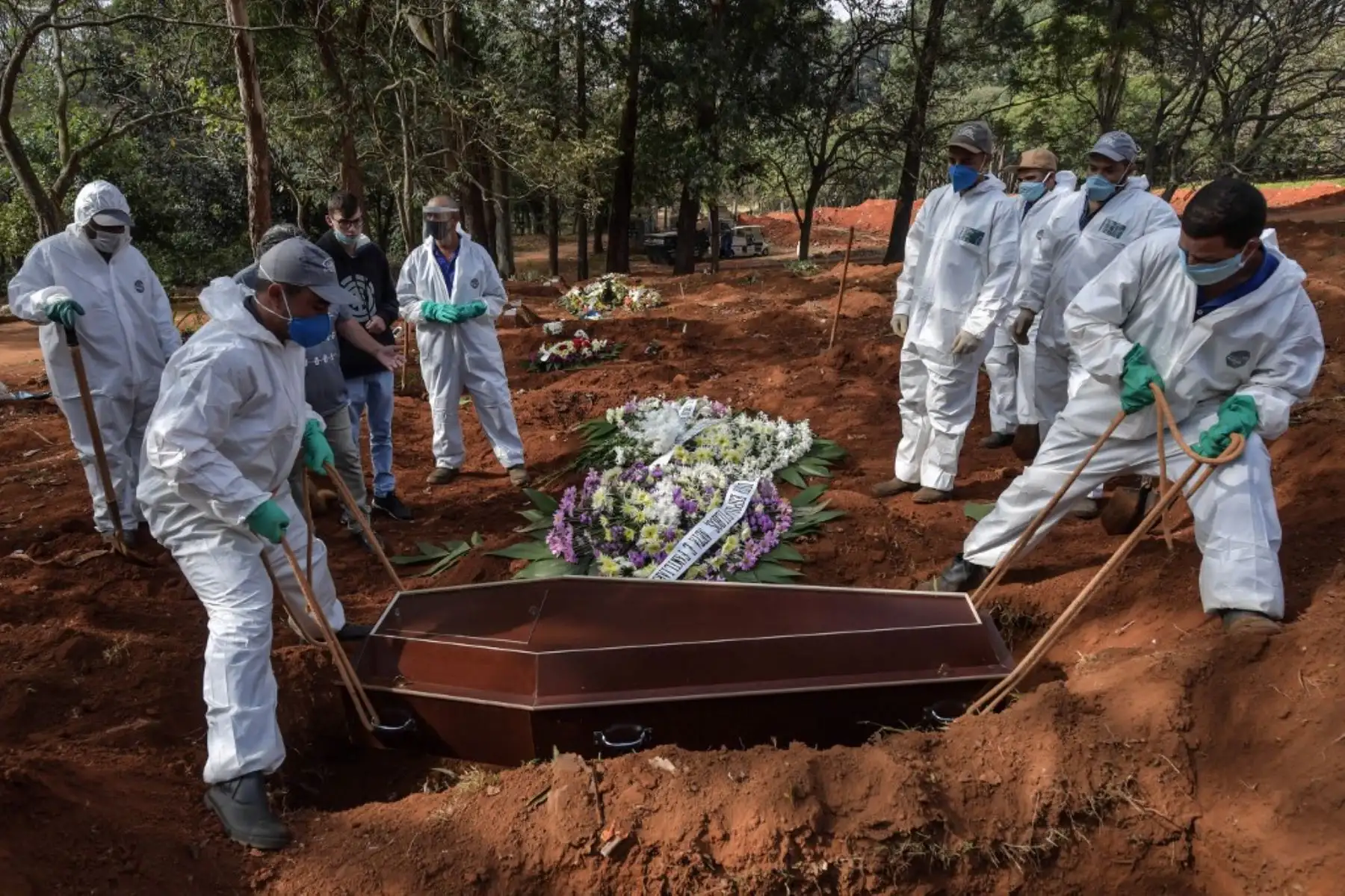 Un grupo empleados entierran el ataúd de una persona que murió por coronavirus en el cementerio de Vila Formosa, en las afueras de Sao Paulo, Brasil. Foto: AFP