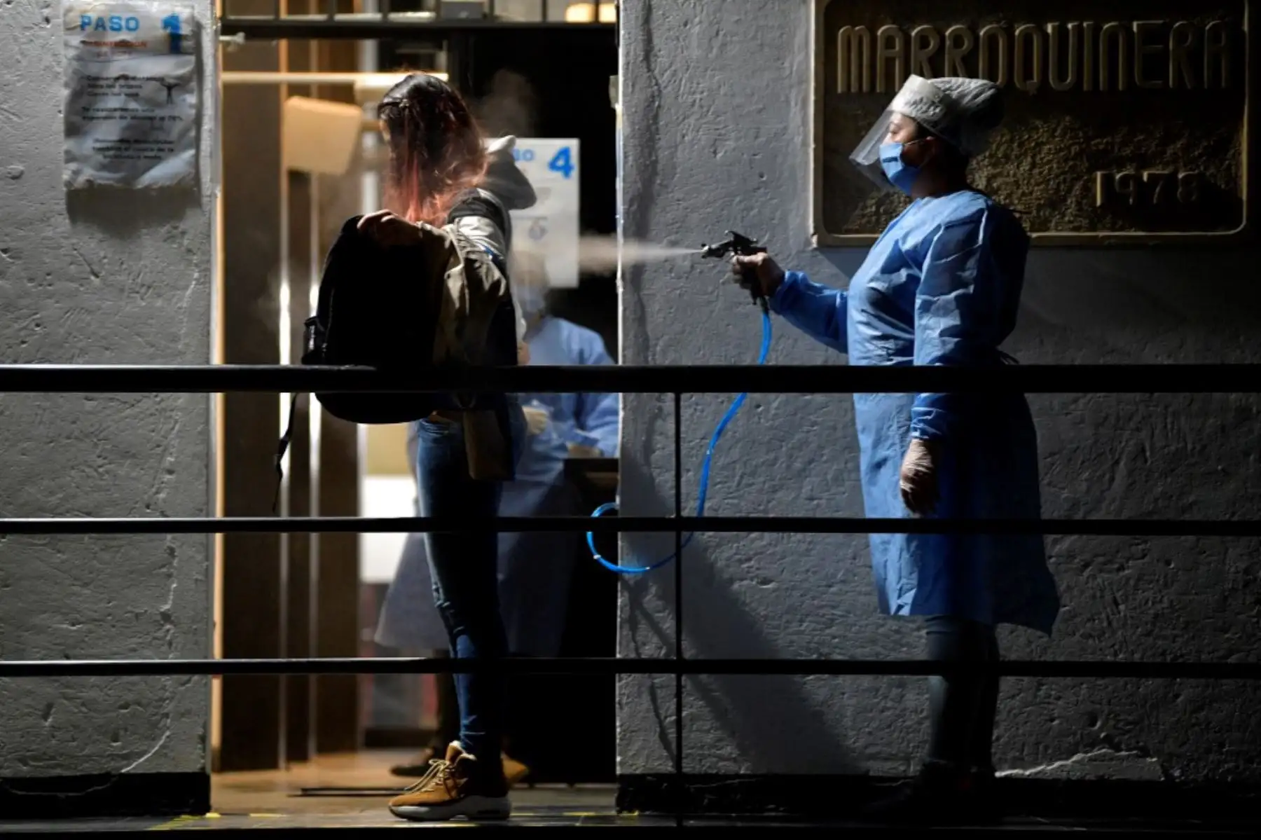 Una mujer desinfecta a un empleado como medida preventiva contra la propagación del nuevo coronavirus en Bogota, Colombia. Foto: AFP