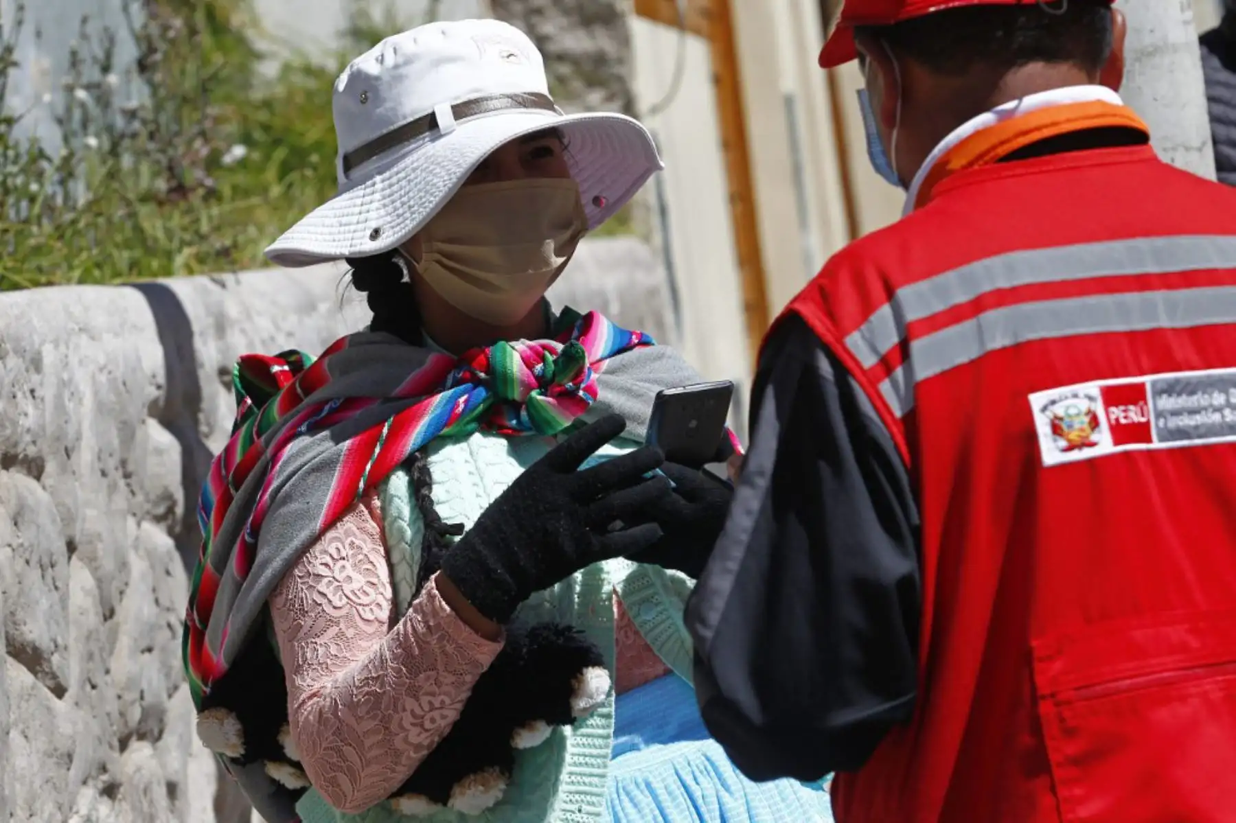 Una mujer con mascarilla es entrevistada por el personal del Ministerio de Mujeres y Poblaciones Vulnerables mientras ocupaba un puesto fuera de la institución Administradora de Fondos de Pensiones, en Puno. Foto: AFP