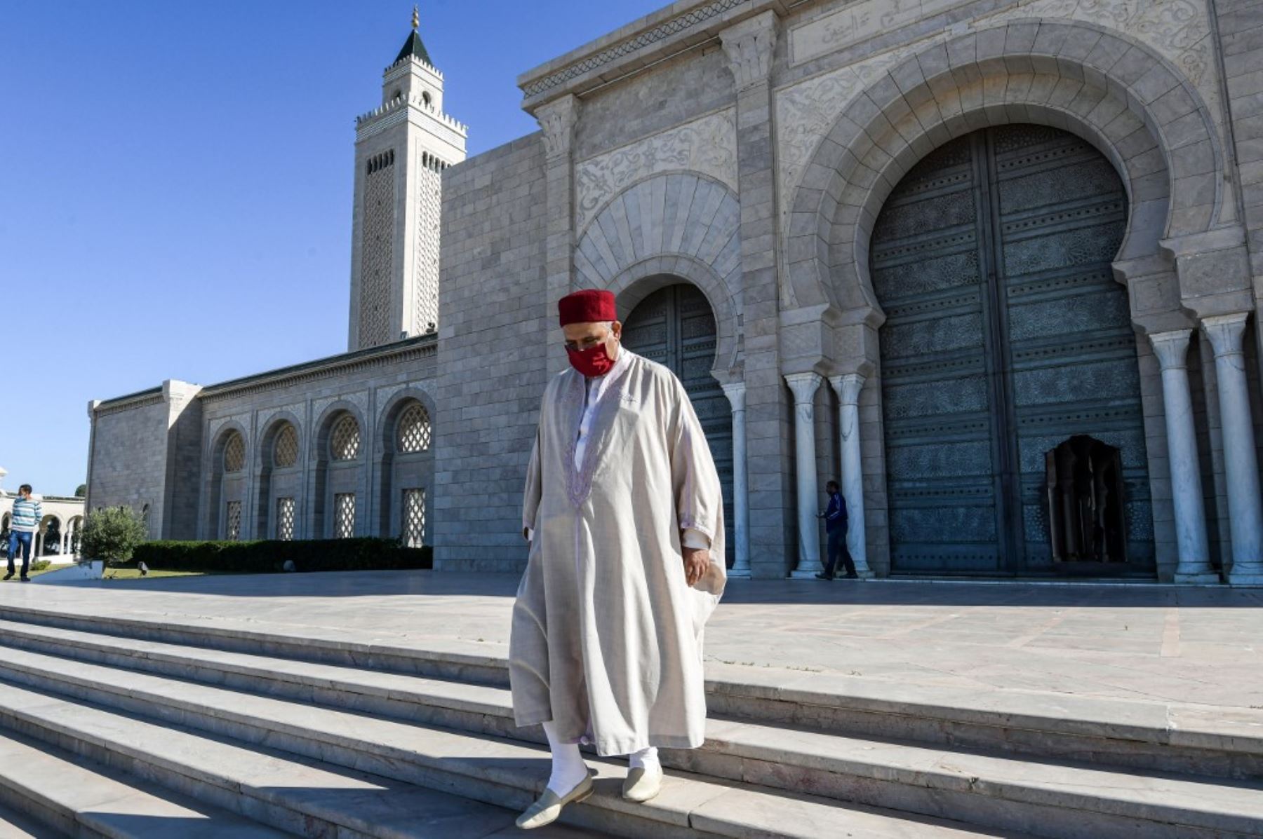 El imán tunecino Mondher Jeddi vestido con una máscara debido a la pandemia del coronavirus  desciende las escaleras a las afueras de la mezquita Malek. Foto: AFP