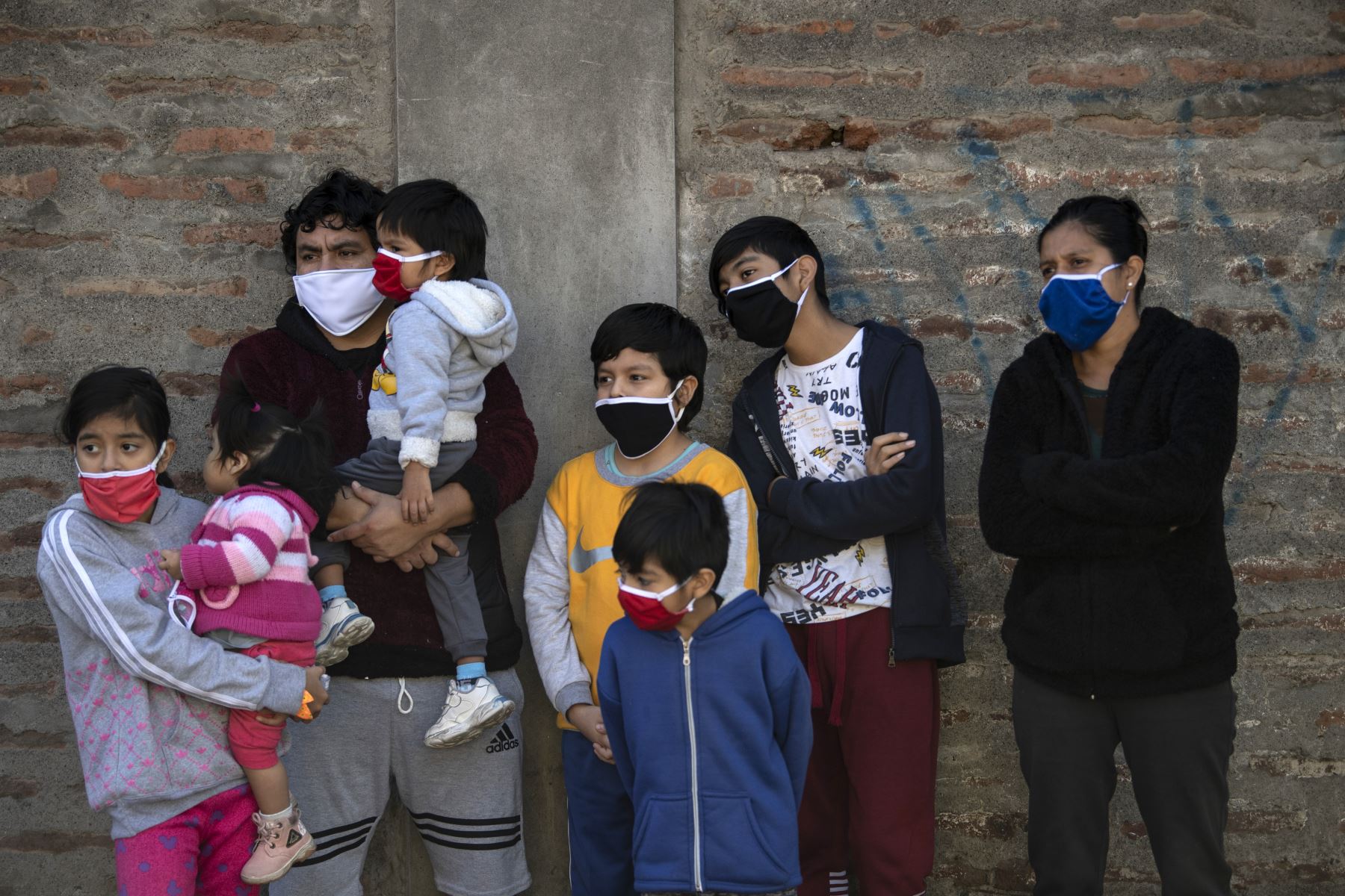 Una familia observa cómo los trabajadores municipales desinfectan un barrio pobre de Santiago. Foto: AFP