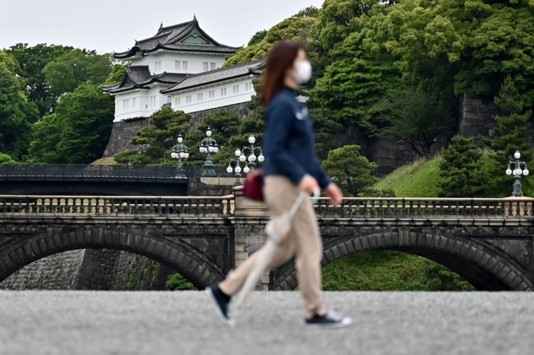 Una mujer con una máscara facial en medio de preocupaciones por el coronavirus COVID-19 camina en una plaza vacía frente al Palacio Imperial, un popular destino turístico, en Tokio. Foto: AFP