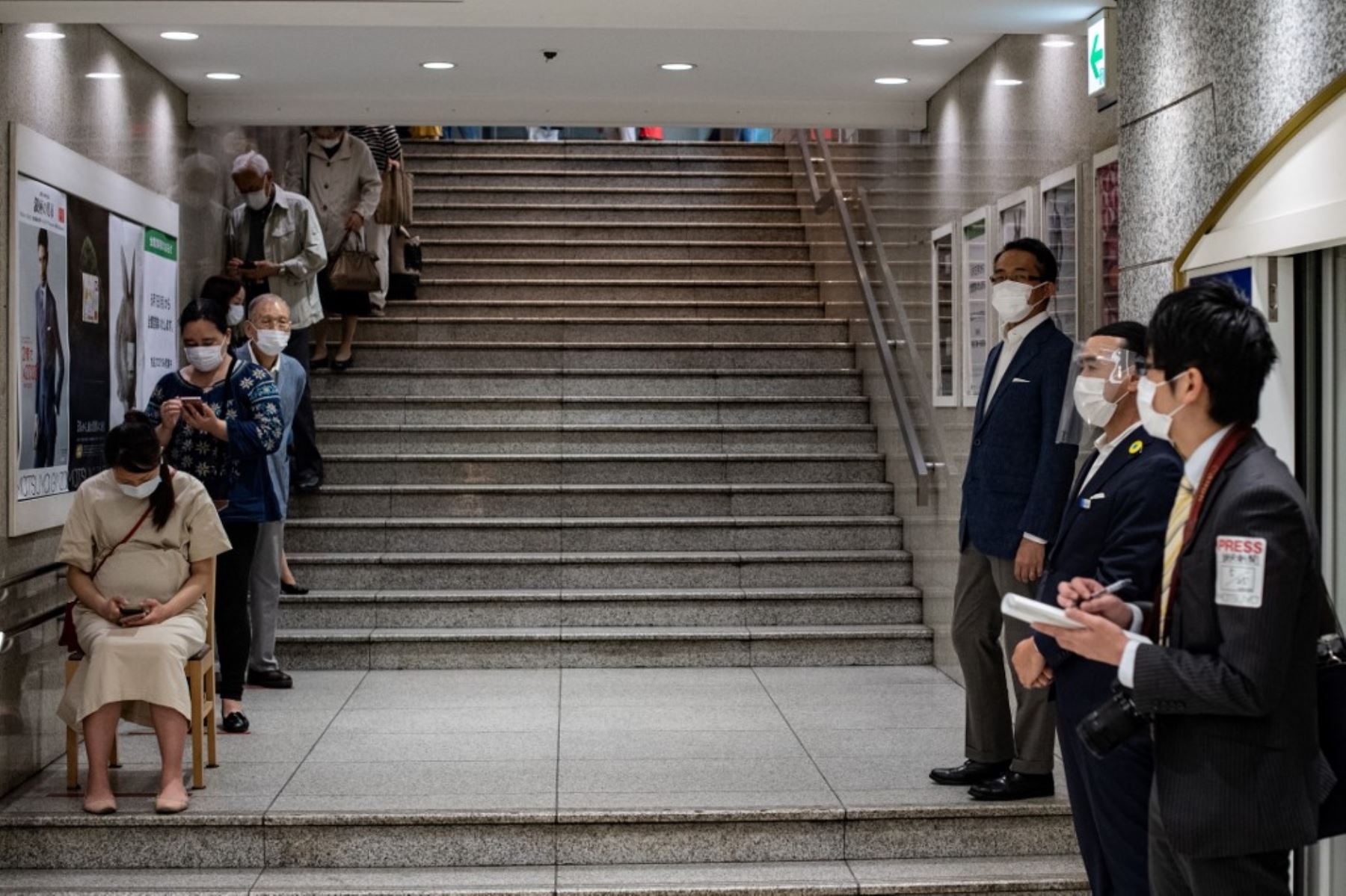 Los miembros del personal (R) con protectores faciales y máscaras esperan mientras los clientes hacen cola para ingresar a los grandes almacenes Matsuya. Foto: AFP