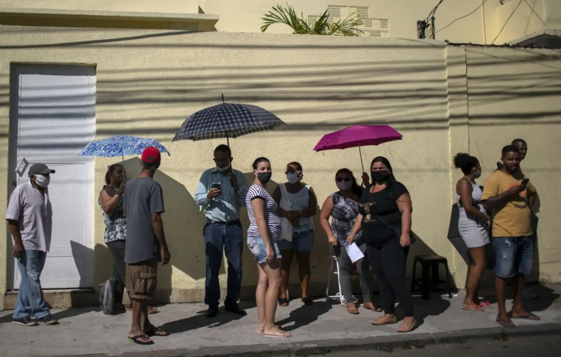 Las personas permanecen fuera del banco Caixa Economica administrado por el gobierno para recibir ayuda económica en medio de la nueva pandemia de coronavirus en Río de Janeiro, Brasil. Foto: AFP