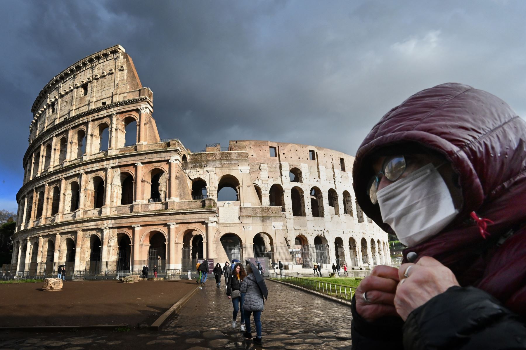 Un hombre con una máscara facial pasa por el monumento del Coliseo en Roma. Foto: AFP