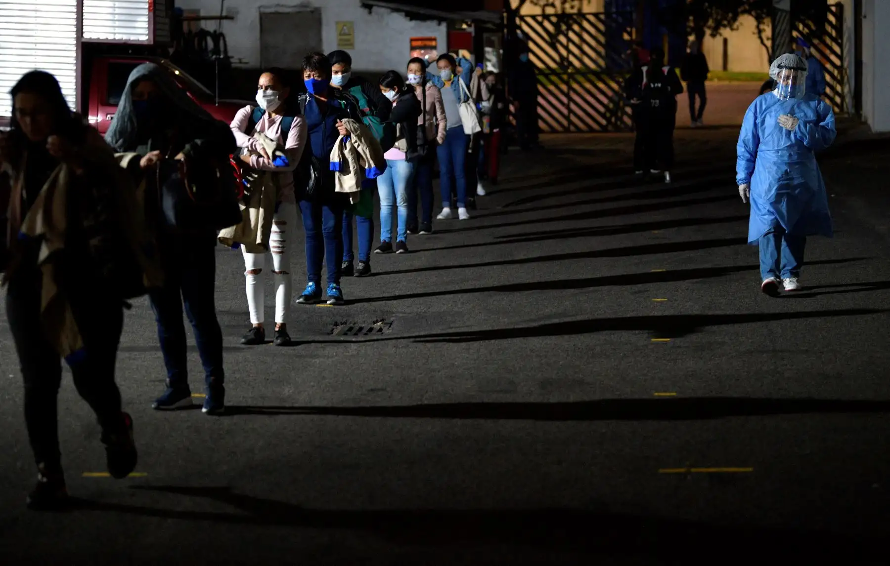 Los empleados hacen cola para ser desinfectados, como medida preventiva contra la propagación del nuevo coronavirus COVID-19, a su llegada a su turno en una fábrica de artículos de cuero en Bogotá. Foto: AFP