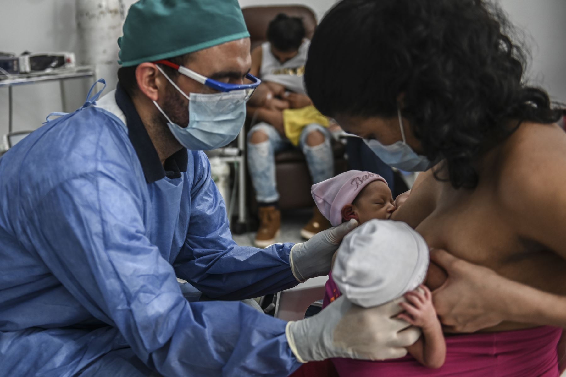 Una madre amamanta a sus gemelos recién nacidos mientras el médico la ayuda, durante la nueva pandemia de coronavirus COVID-19. Foto: AFP