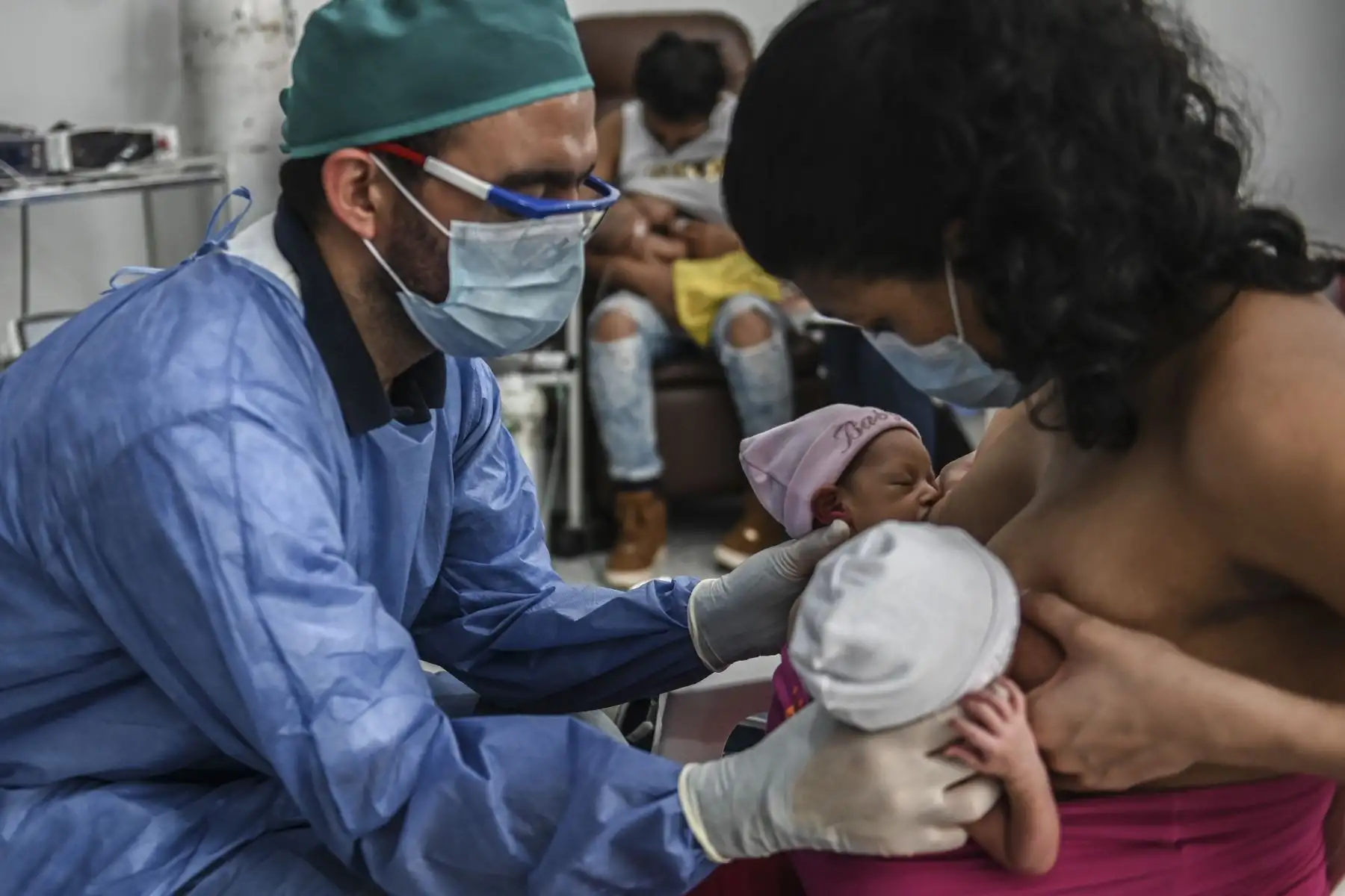 Una madre amamanta a sus gemelos recién nacidos mientras el médico la ayuda, durante la nueva pandemia de coronavirus COVID-19. Foto: AFP