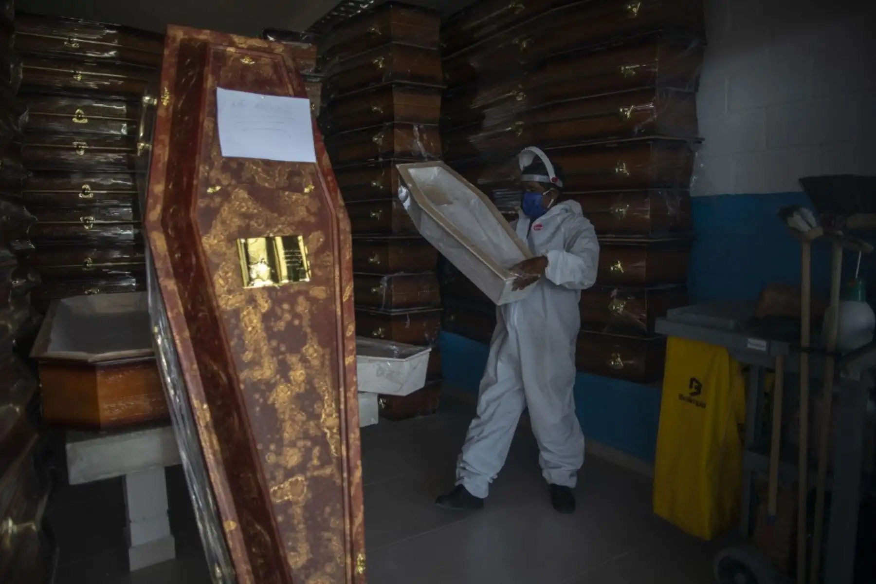 Un sepulturero con equipo de protección personal organiza ataúdes en el Cementerio Público de Duque de Caxias, en el estado de Río de Janeiro. Foto: AFP