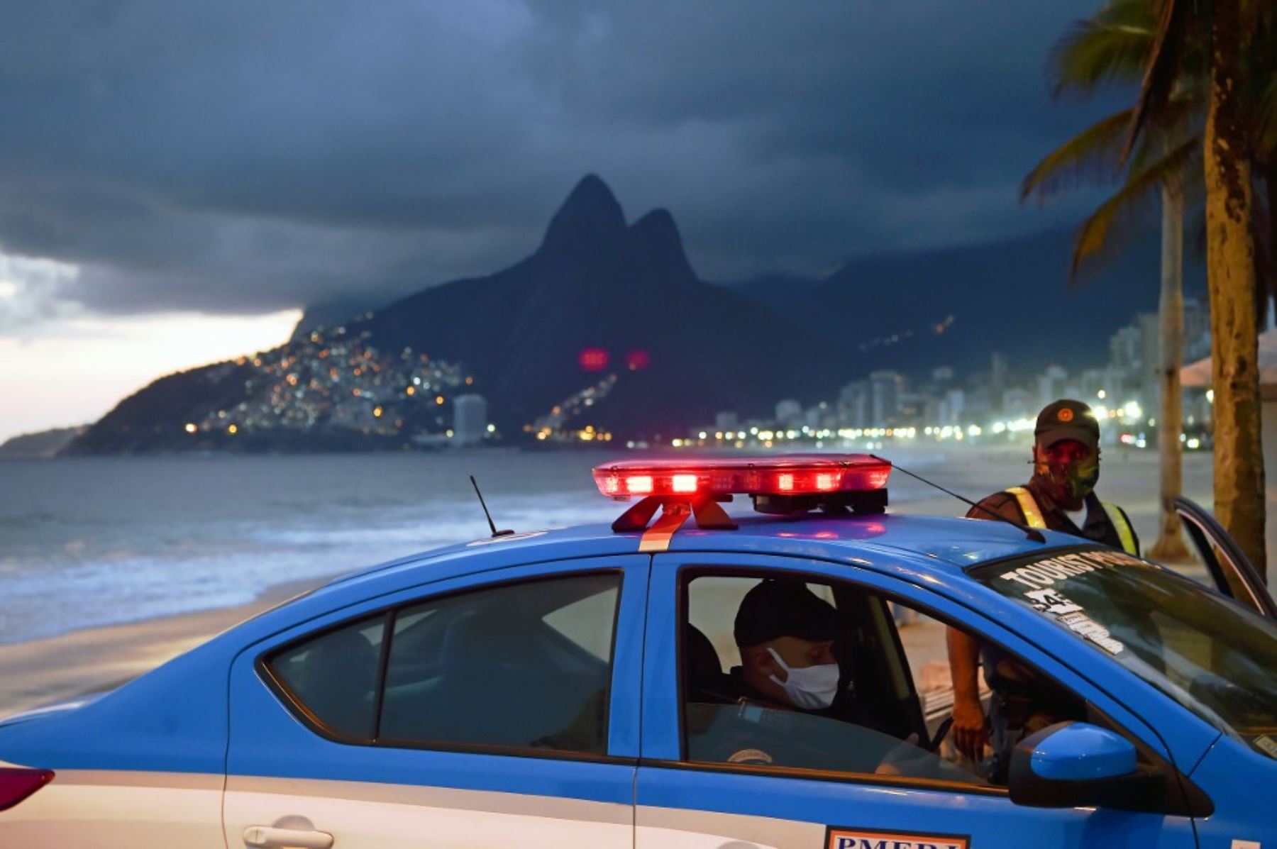 La policía con mascarillas como medida contra la propagación del nuevo coronavirus se ve con su automóvil en la playa de Ipanema en Río de Janeiro, Brasil. Foto: AFP